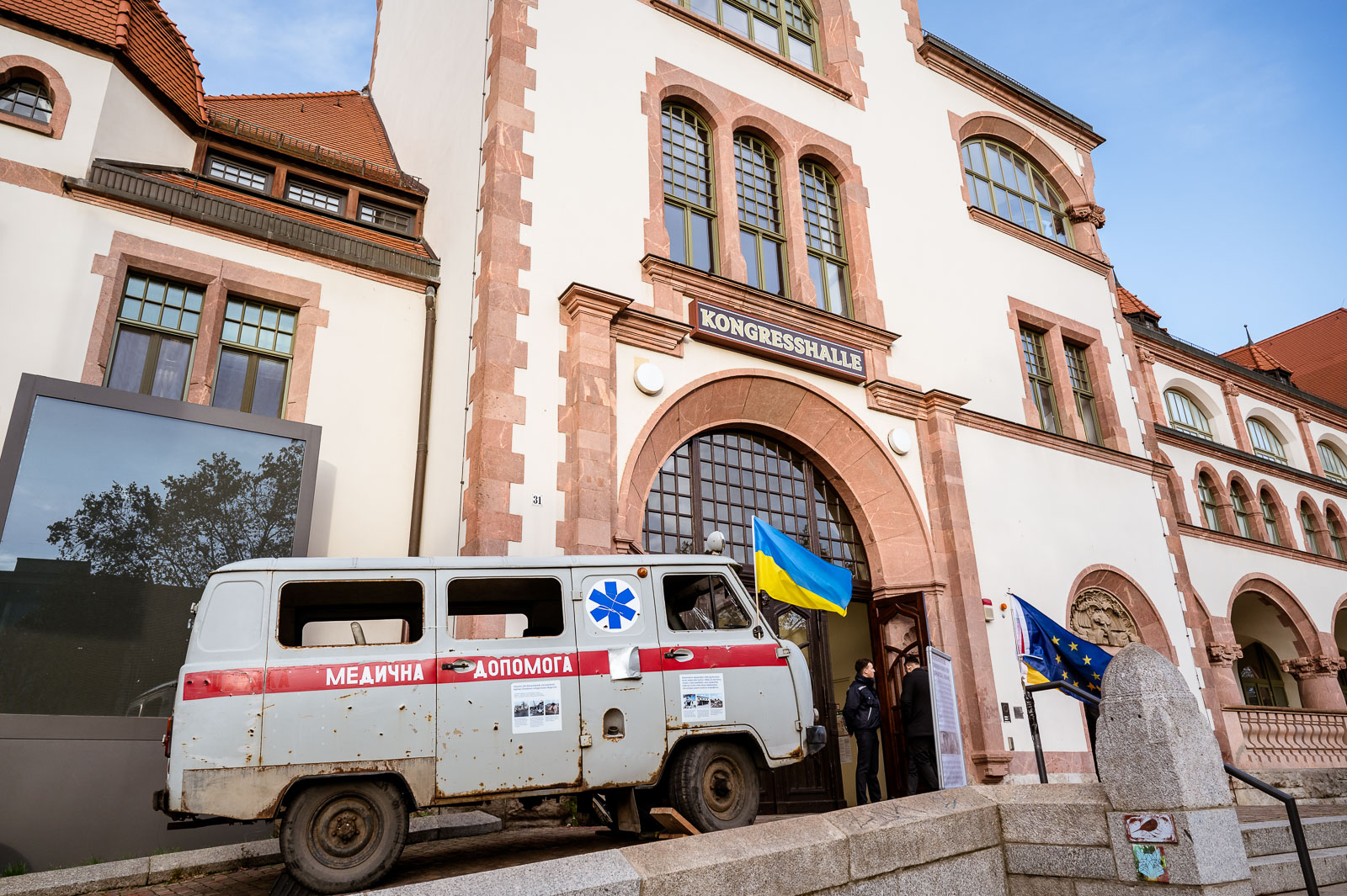 A destroyed ambulance from Ukraine stands in front of the Congress Hall in Leipzig, the venue for the German-Ukrainian municipal partnership conference.