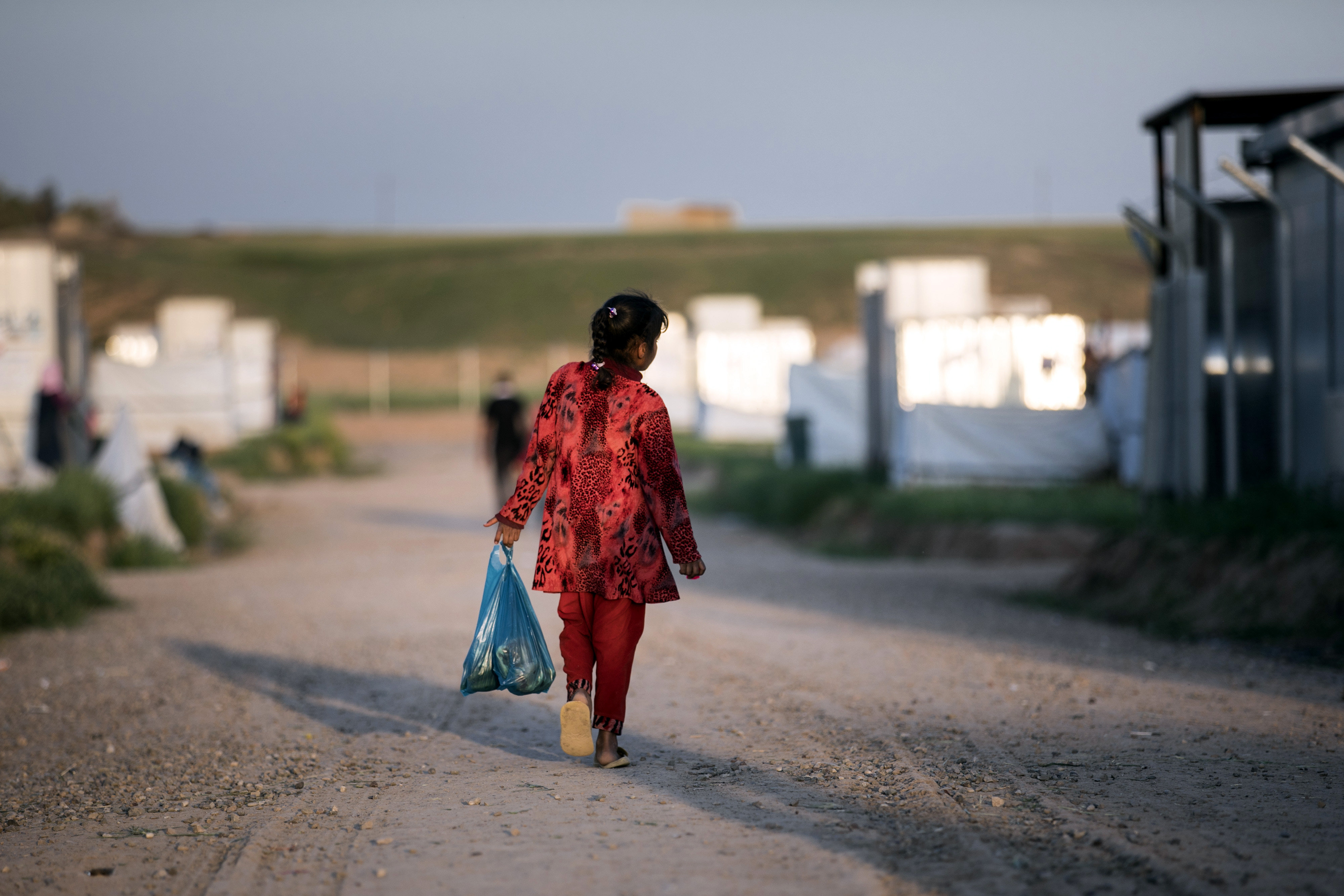 Ein Mädchen geht mit einer Plastiktüte, gefüllt mit Lebensmitteln, durch ein Flüchtlings-Camp im Irak