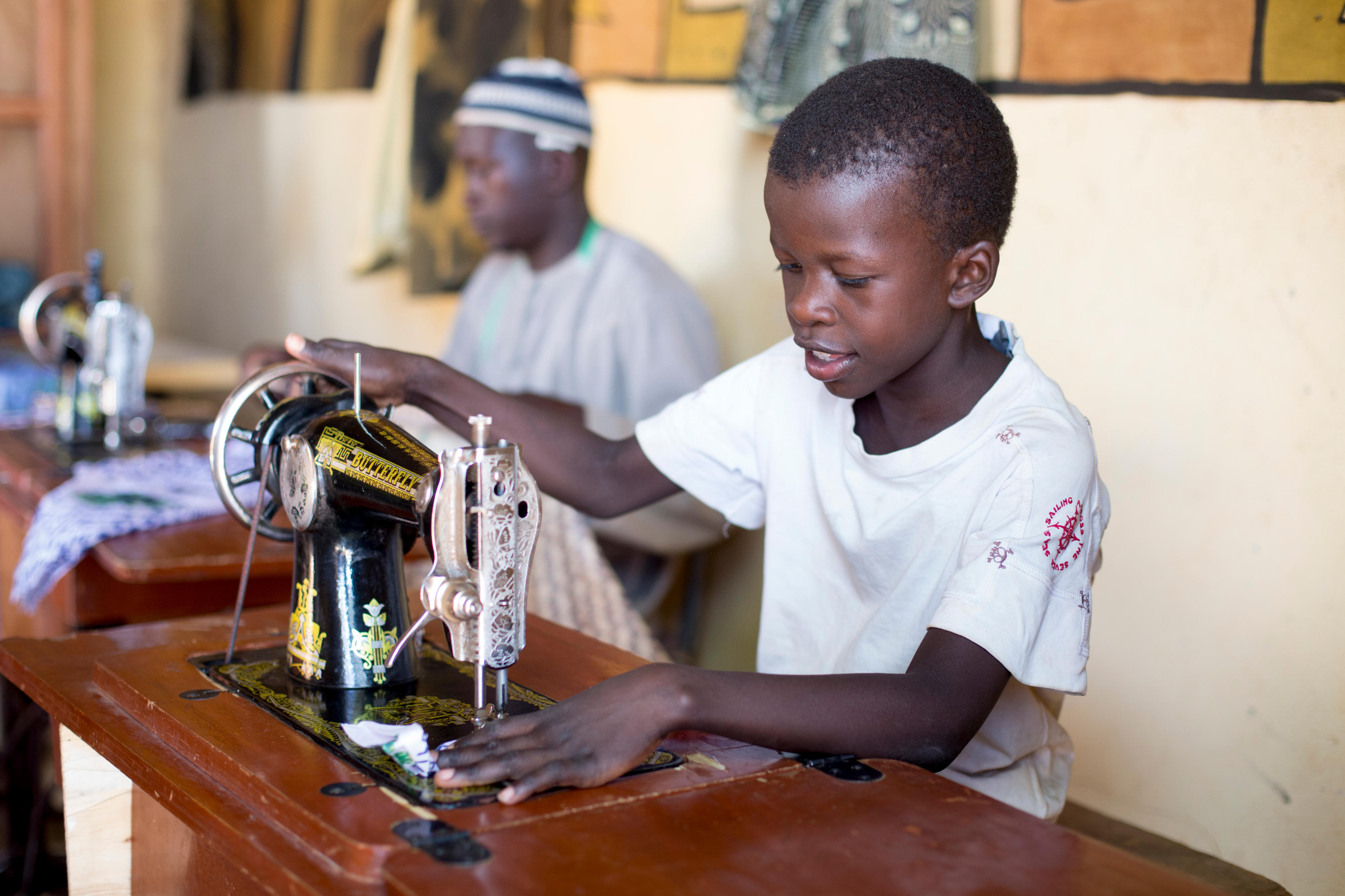 Ein Junge in Mali arbeitet an einer Nähmaschine.