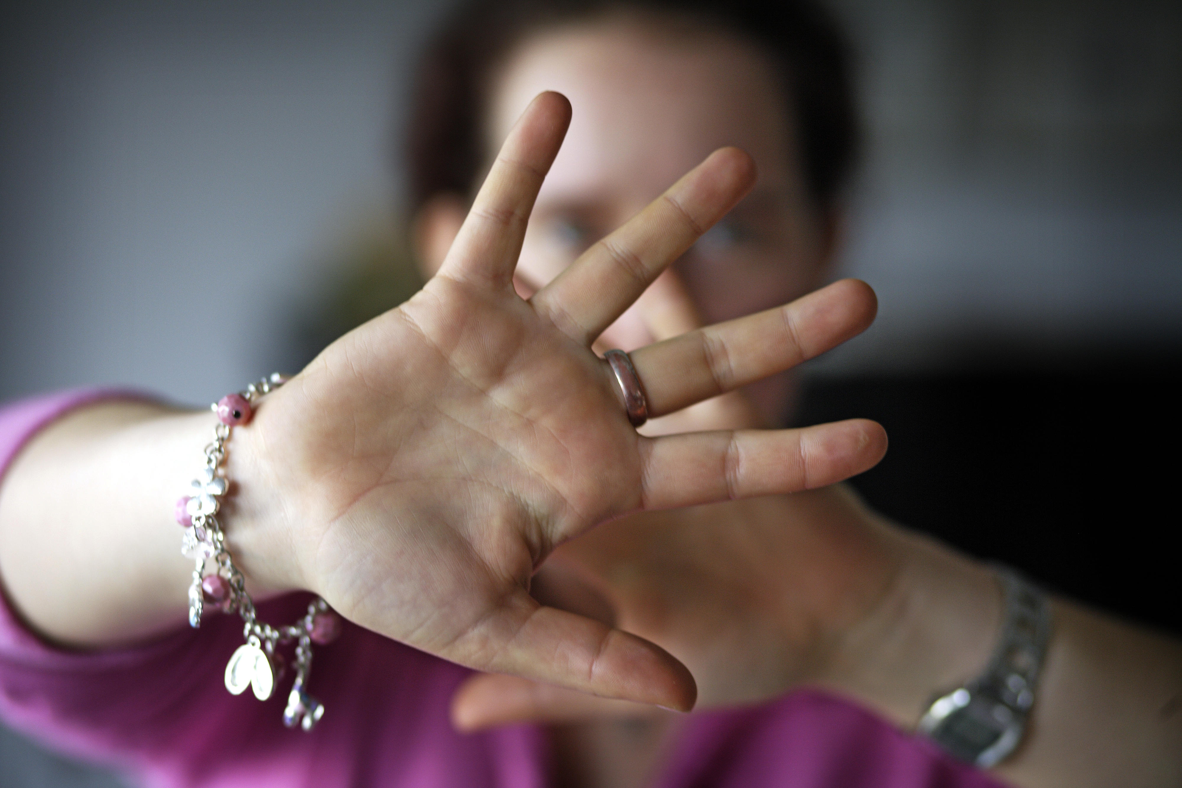 Symbolfoto: Eine Frau hält abwehrend ihre Hände vor ihren Kopf um sich zu schützen