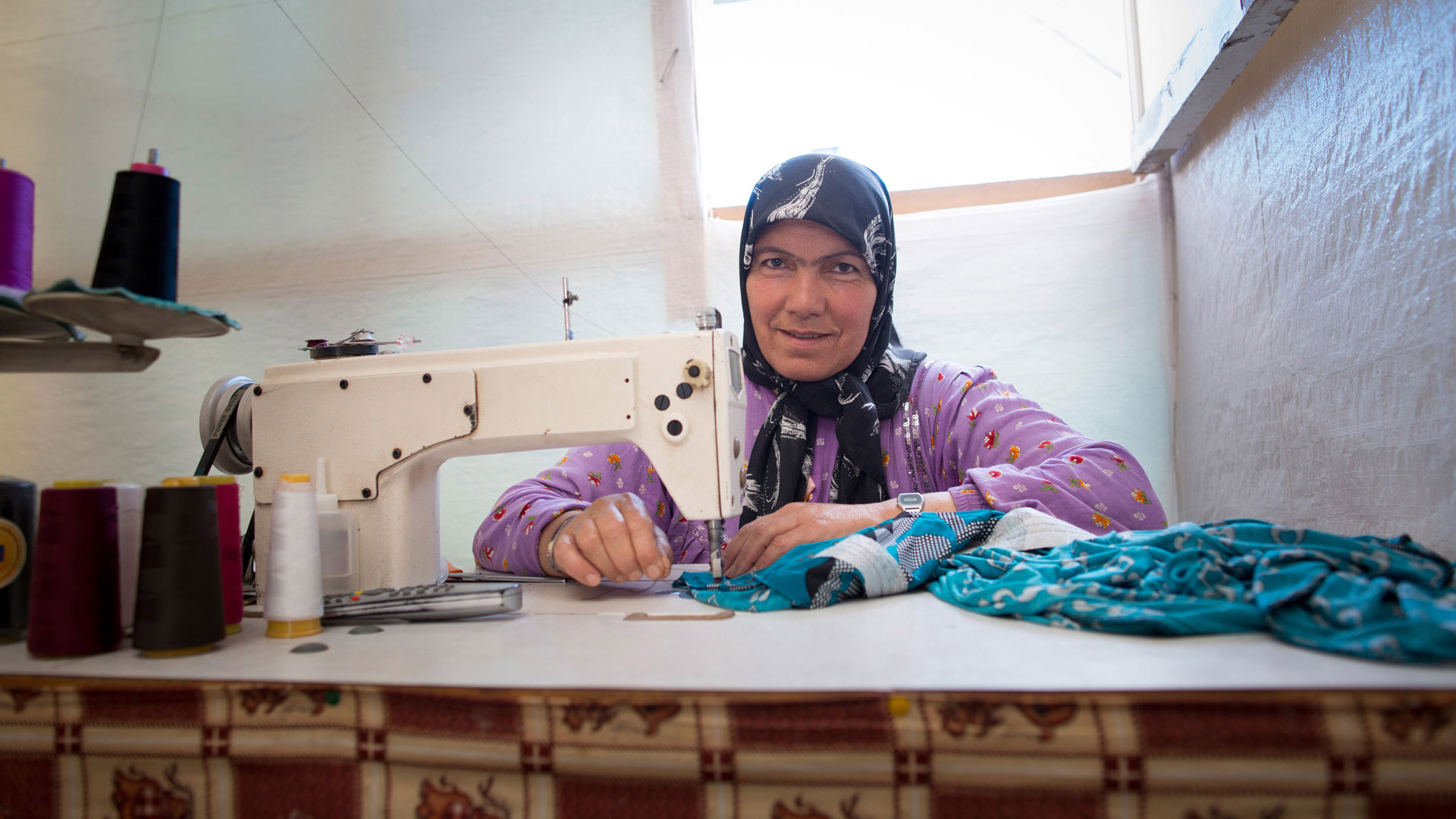 Eine Frau in einem Flüchtlingslager im Libanon kann als Schneiderin etwas Geld für ihre Familie verdienen.