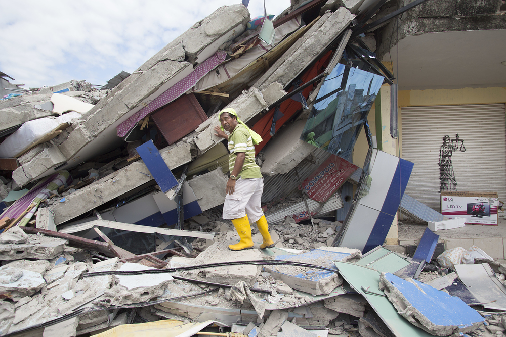 A volunteer rescue worker searches through the rubble of a house after an earthquake in Pedernales, Ecuador (April 2016).
