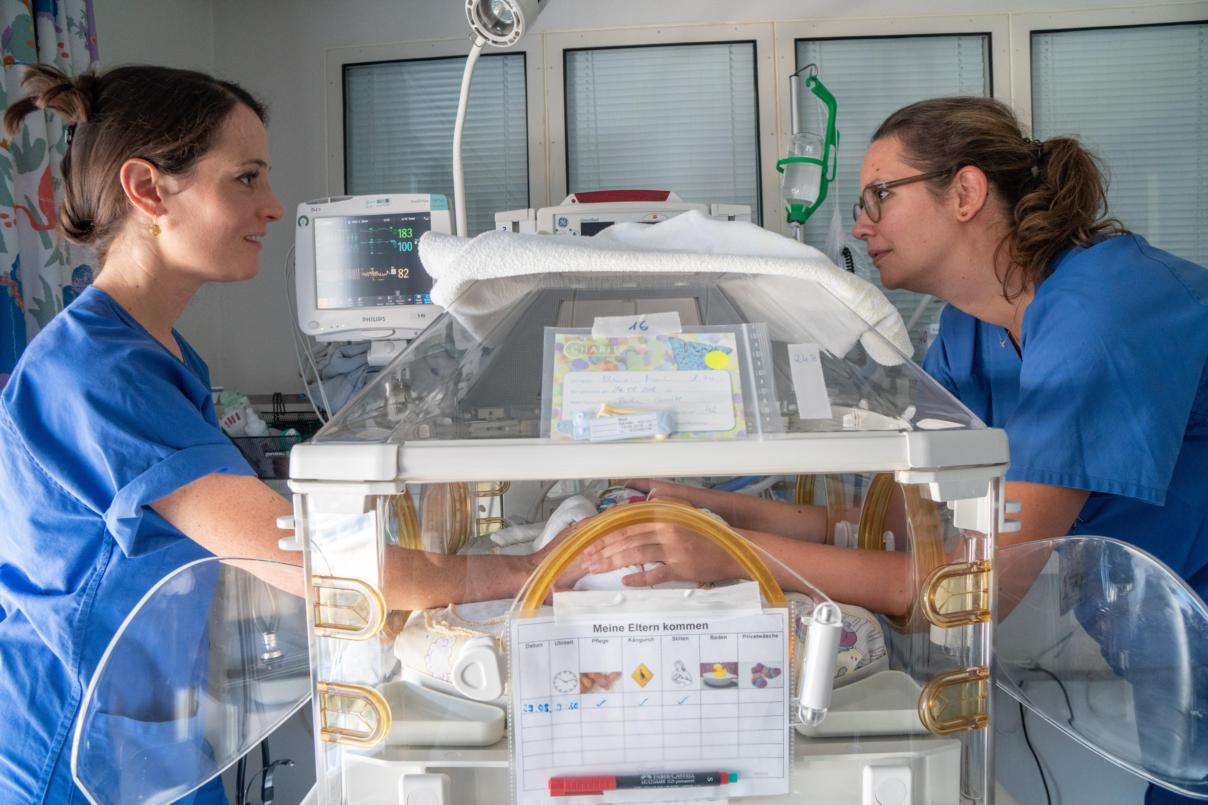 Fachkräfte der Charité – Universitätsmedizin Berlin kümmern sich um ein Neugeborenes in einem Inkubator.