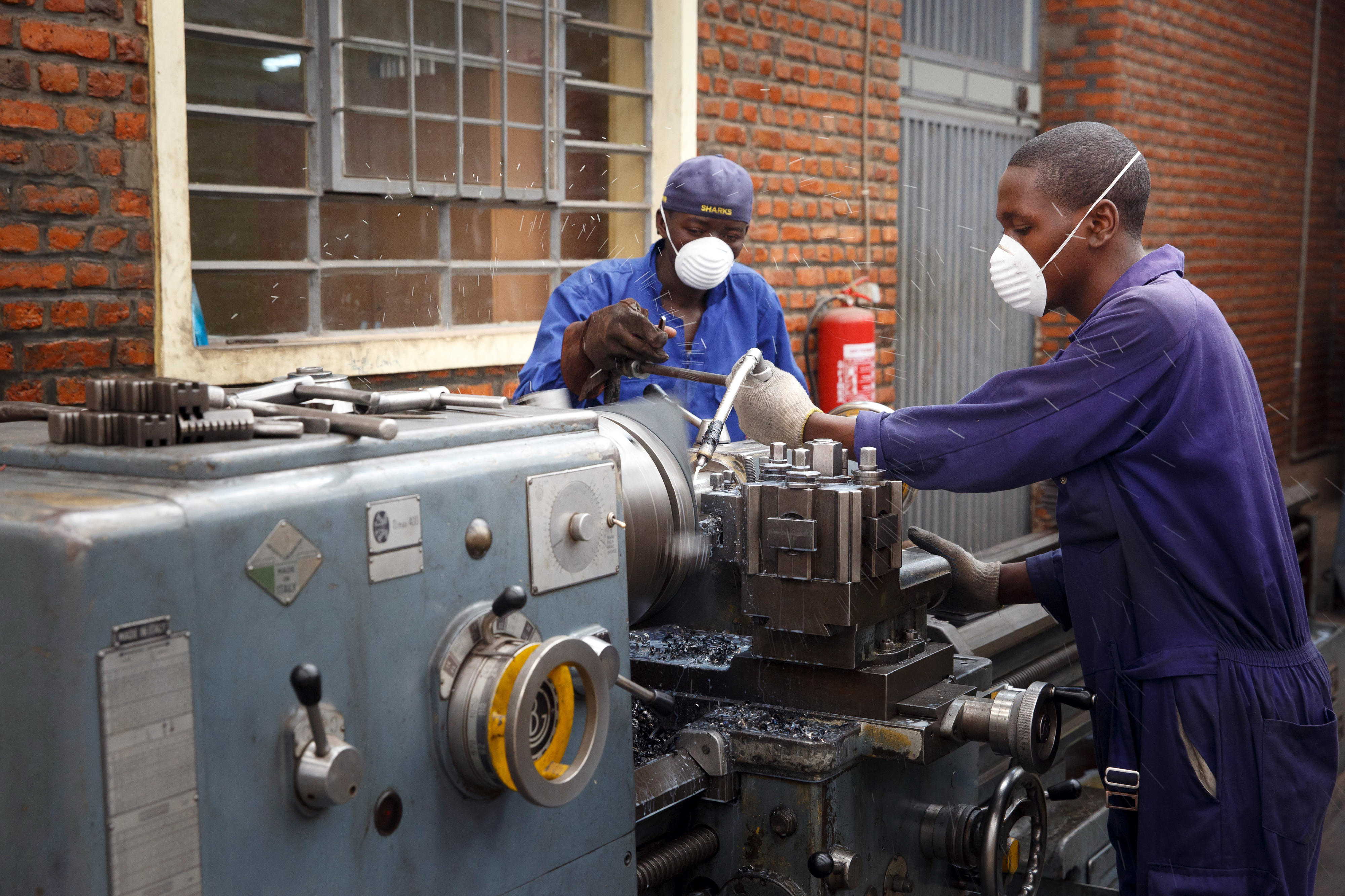Two trainees in metal construction at the Integrated Polytechnical Regional College (IPRC) in Kigali, Rwanda, operate a machine.