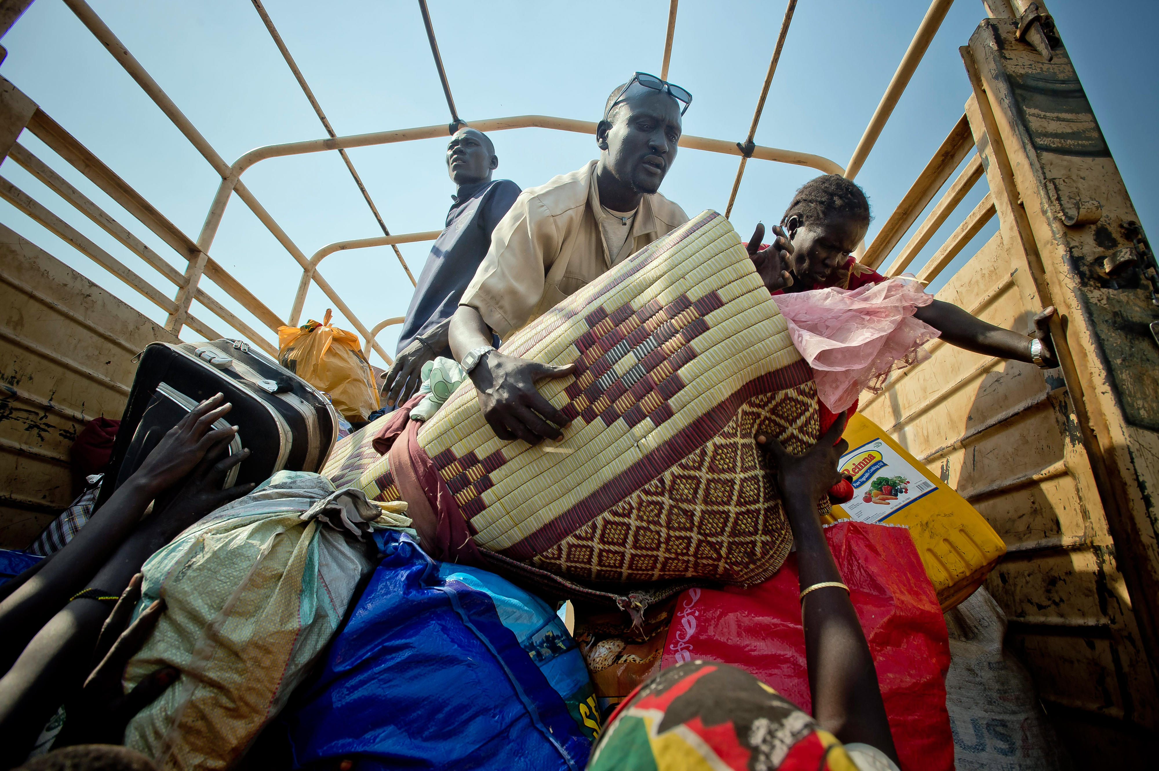 Südsudanesische Flüchtlinge an der Grenze zu Uganda verstauen ihre Habseligkeiten auf einem LKW.