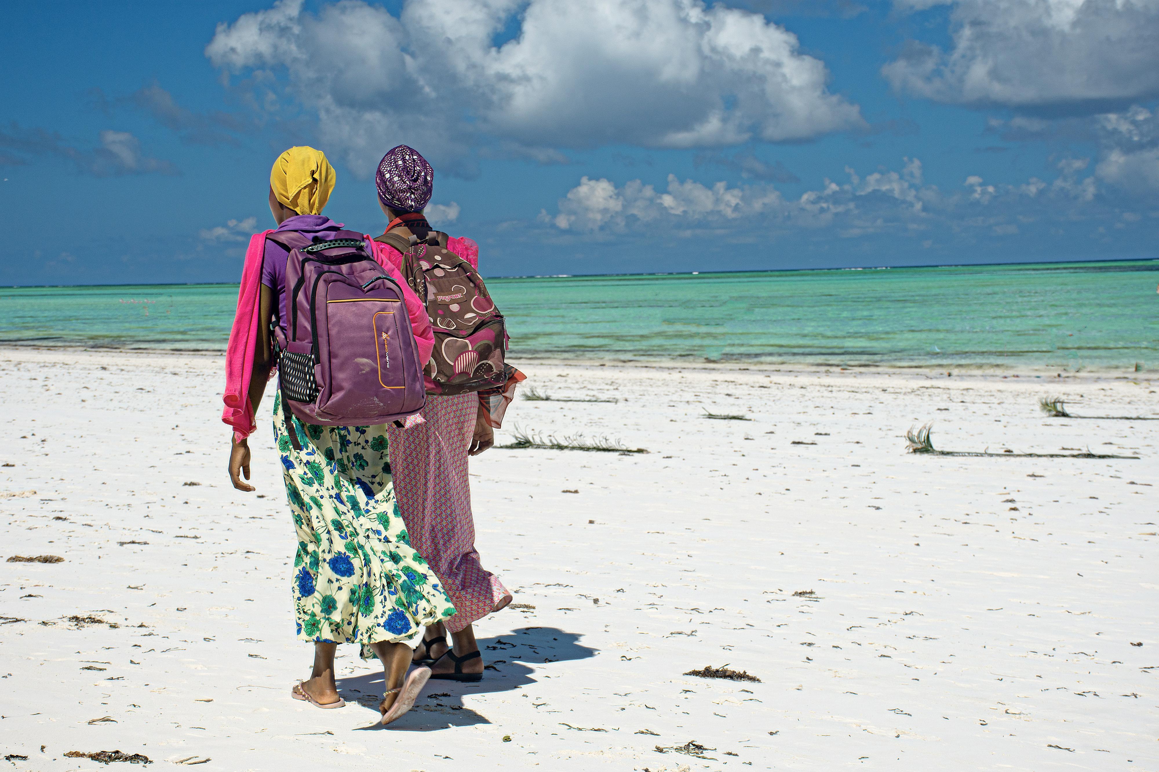 Schoolgirls on their way to school on a beach on the island of Zanzibar, which is part of Tanzania.