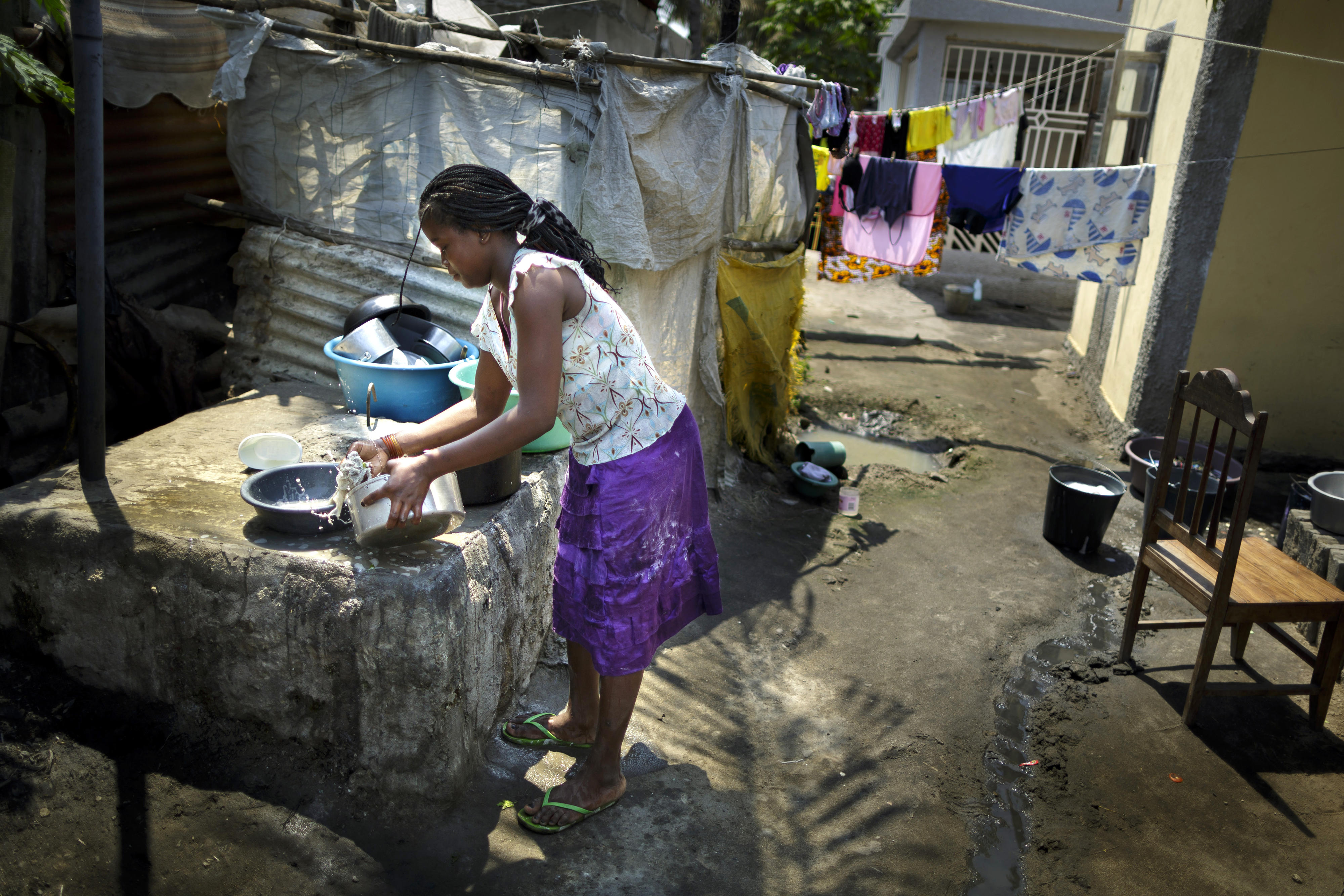 Eine junge Frau wäscht in einem Slum im Stadtgebiet von Beira, Mosambik, Geschirr ab.
