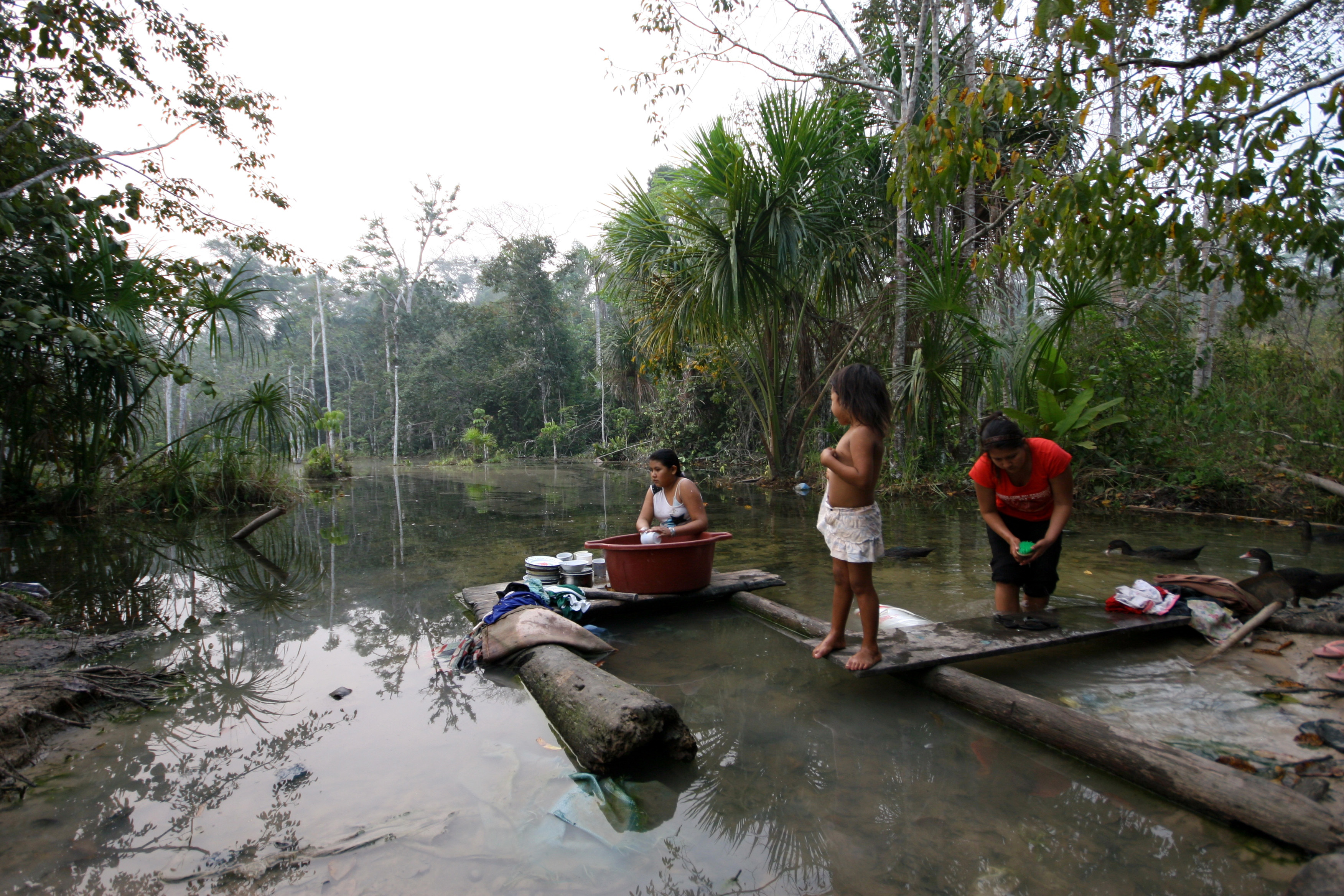 Bolivian women cleaning dishes in a river.