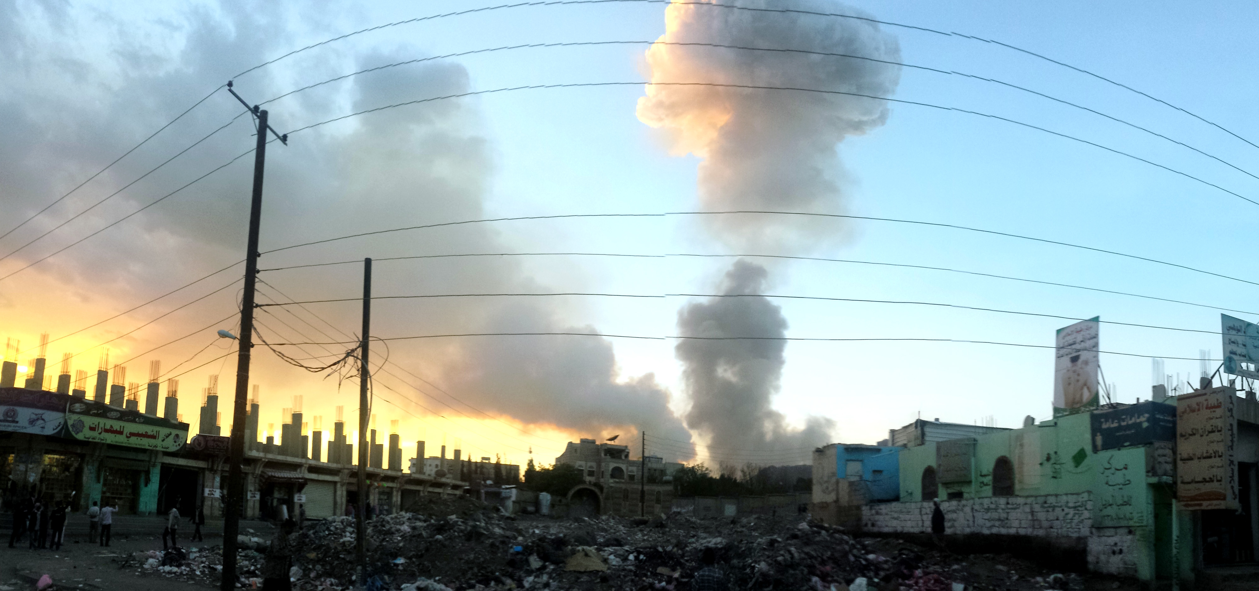 Luftangriff in Sanaa, Jemen, 5. November 2015: Ein Rauchpilz steigt im Hintergrund auf, im Vordergrund Trümmer und Ruinen von Häusern. aus