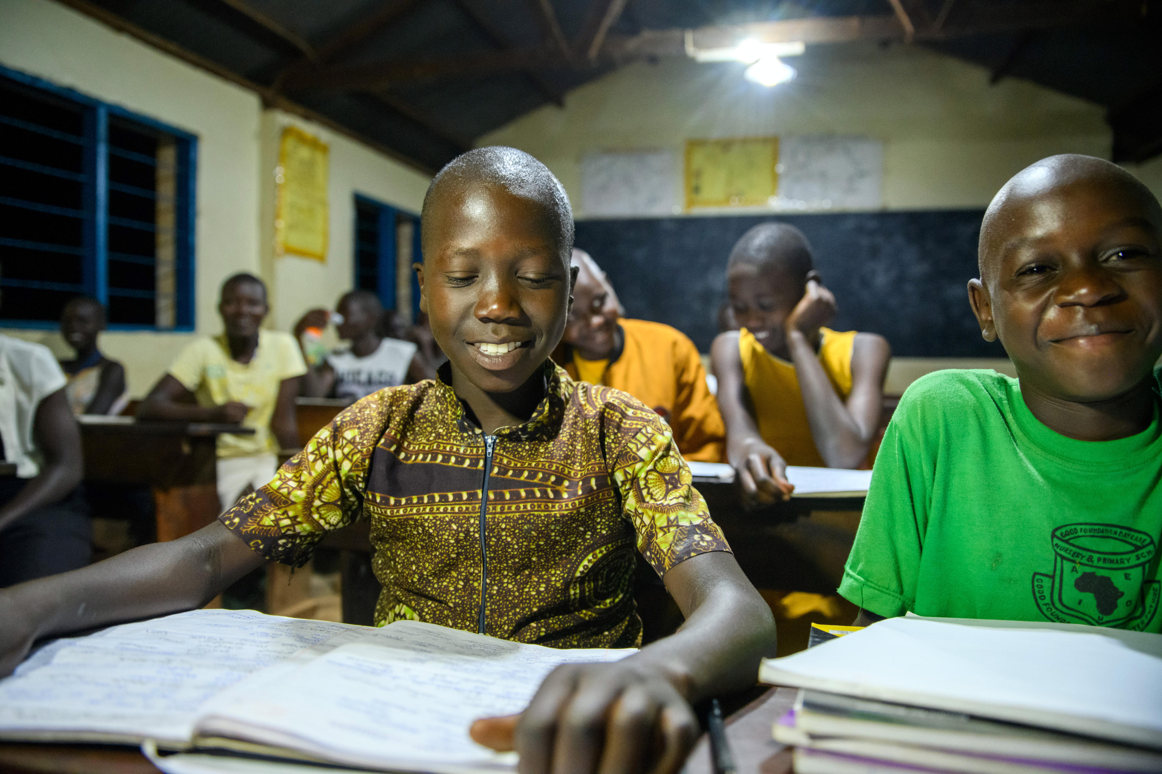 Kinder in einem Klassenzimmer in Norduganda, das mit Solarstrom beleuchtet wird.