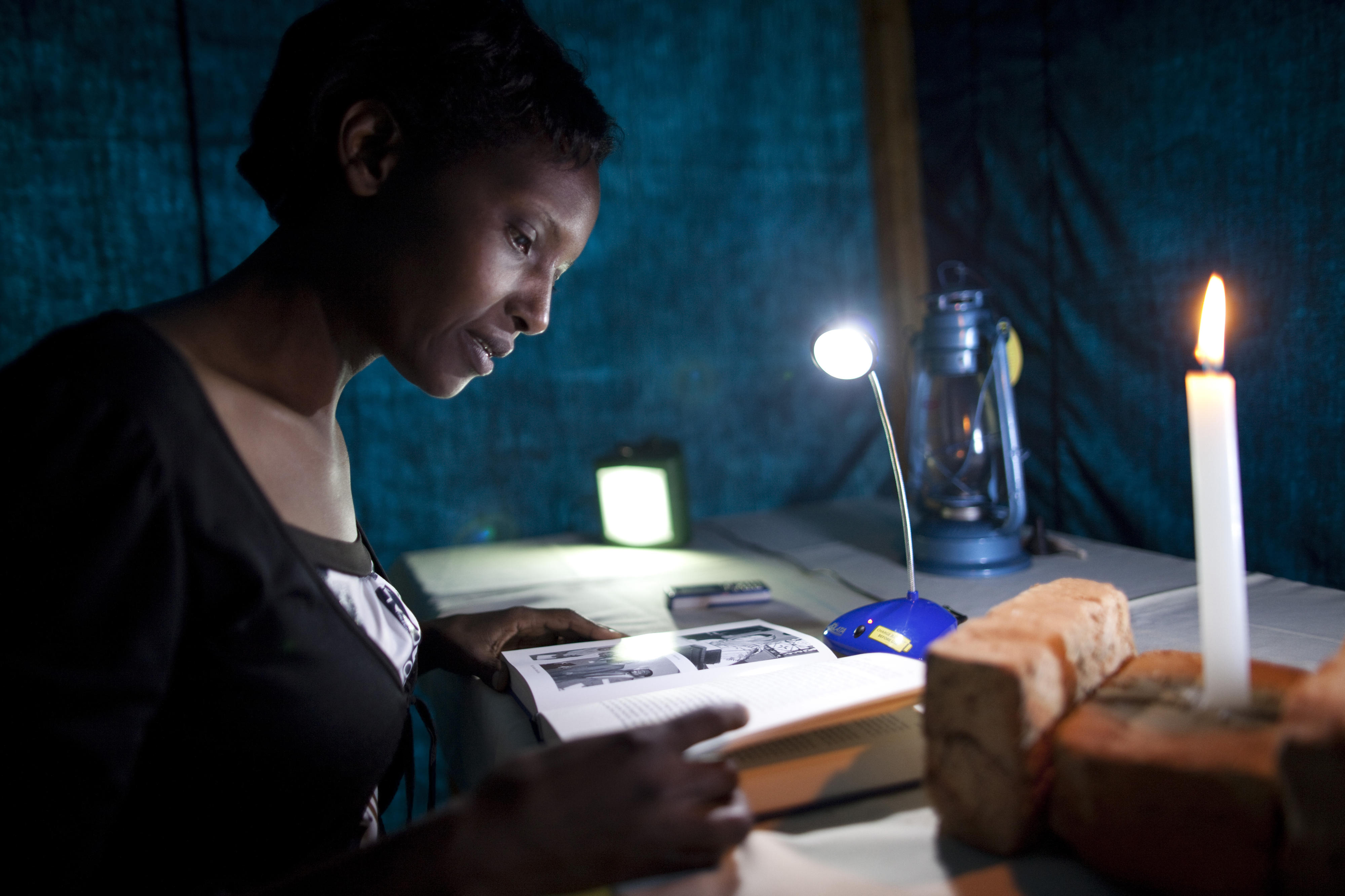 A woman in Burundi reads by the light of a solar-powered table lamp.