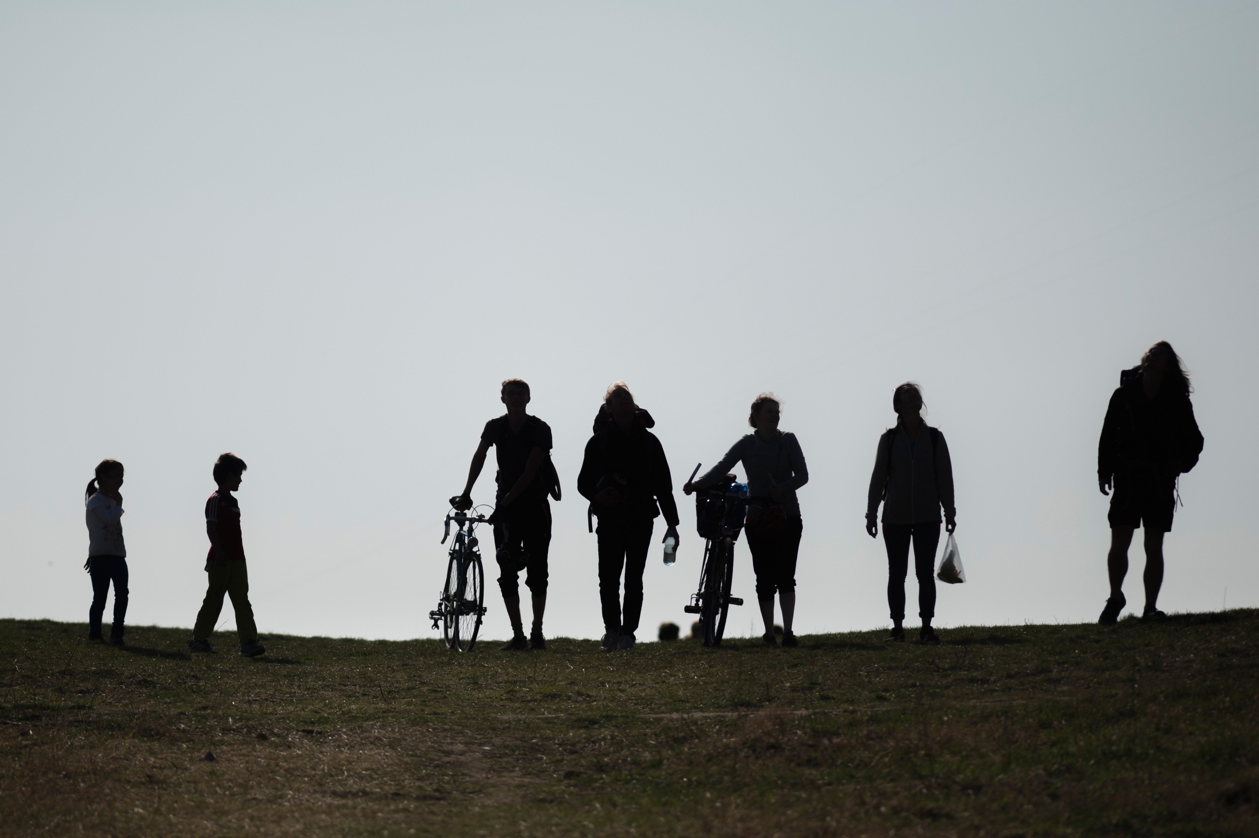 Silhouetten von Menschen, die auf einen Hügel steigen