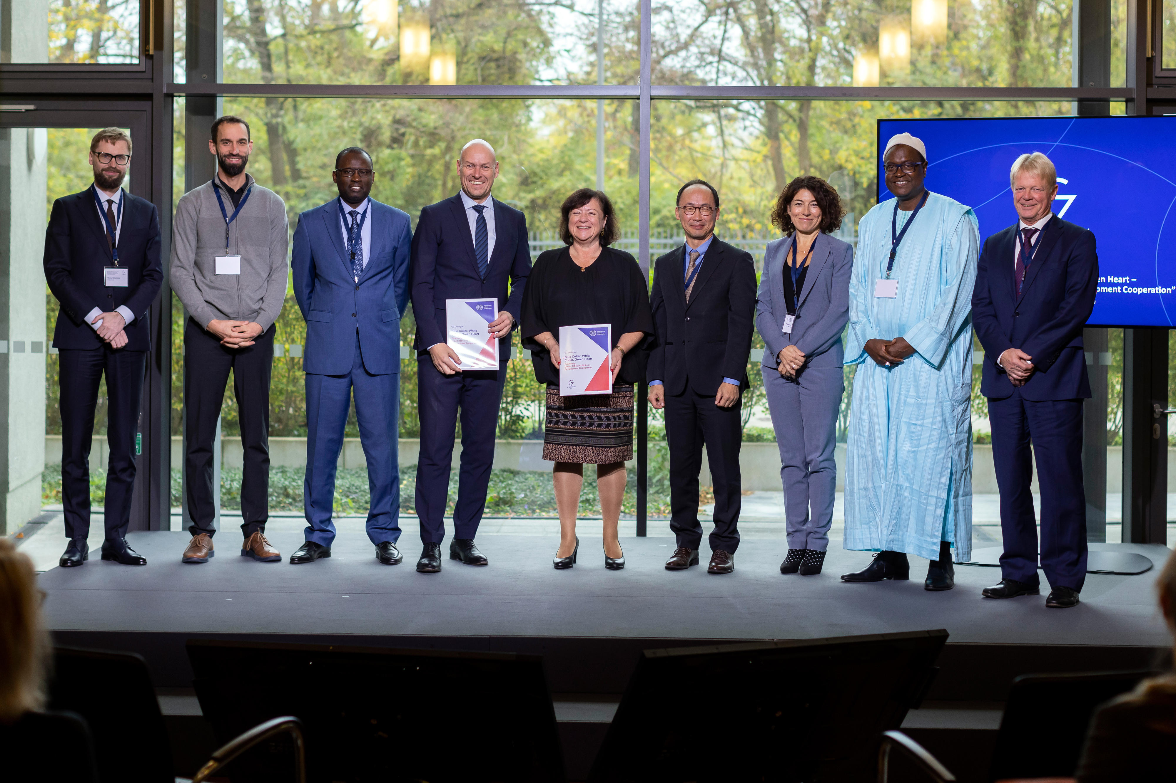 Die Parlamentarische Staatssekretärin Bärbel Kofler und Sangheon Lee, Direktor für Beschäftigungspolitik der Internationalen Arbeitsorganisation (ILO), sowie weitere Teilnehmerinnen und Teilnehmer des G7-Dialogforums bei der Übergabe der Vorschläge, wie die G7-Verpflichtung zur Förderung grüner Arbeitsplätze gemessen und evaluiert werden kann.