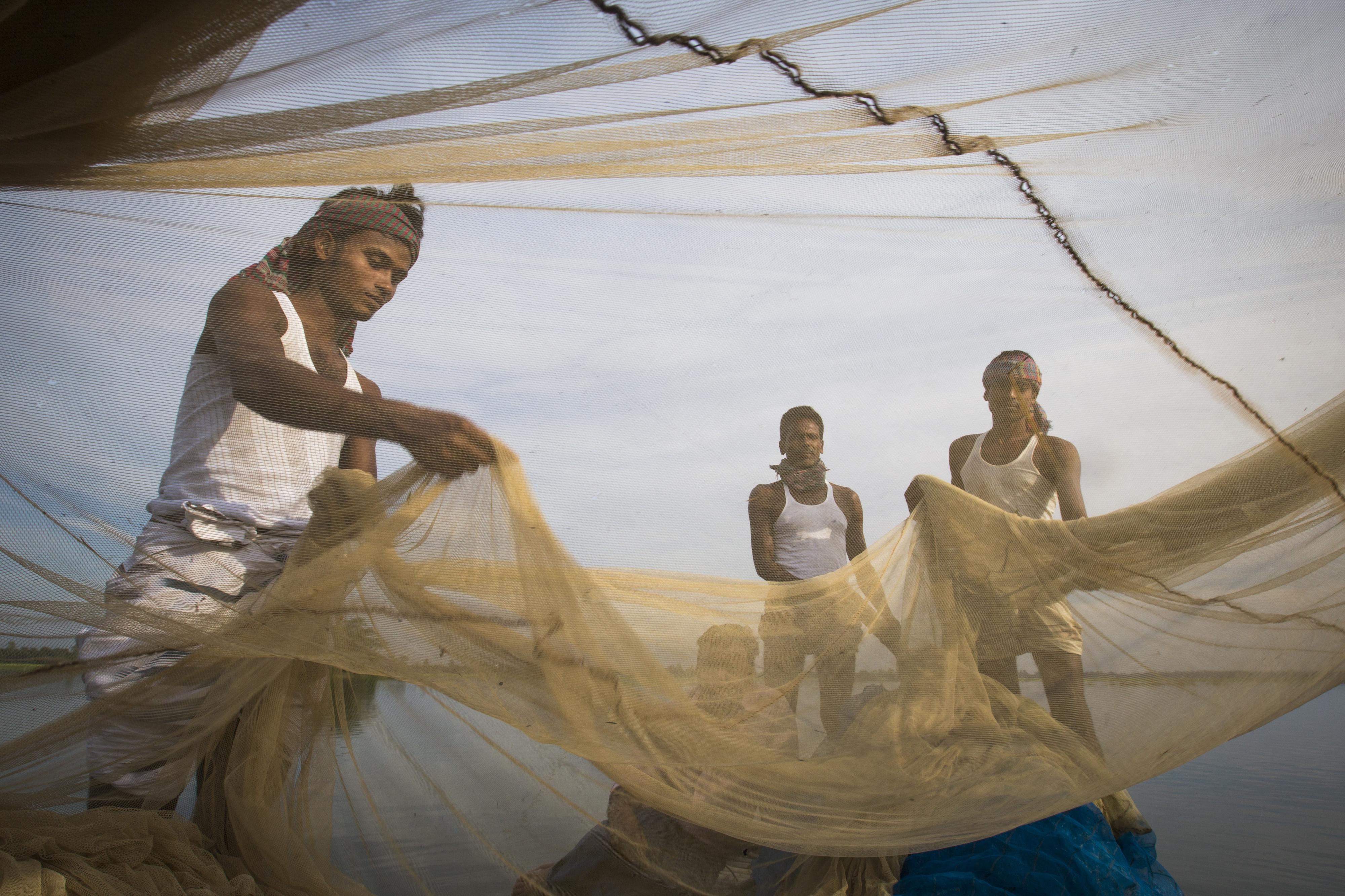 Symbolic image on the subject of the social safety net: Three fishermen hold a net
