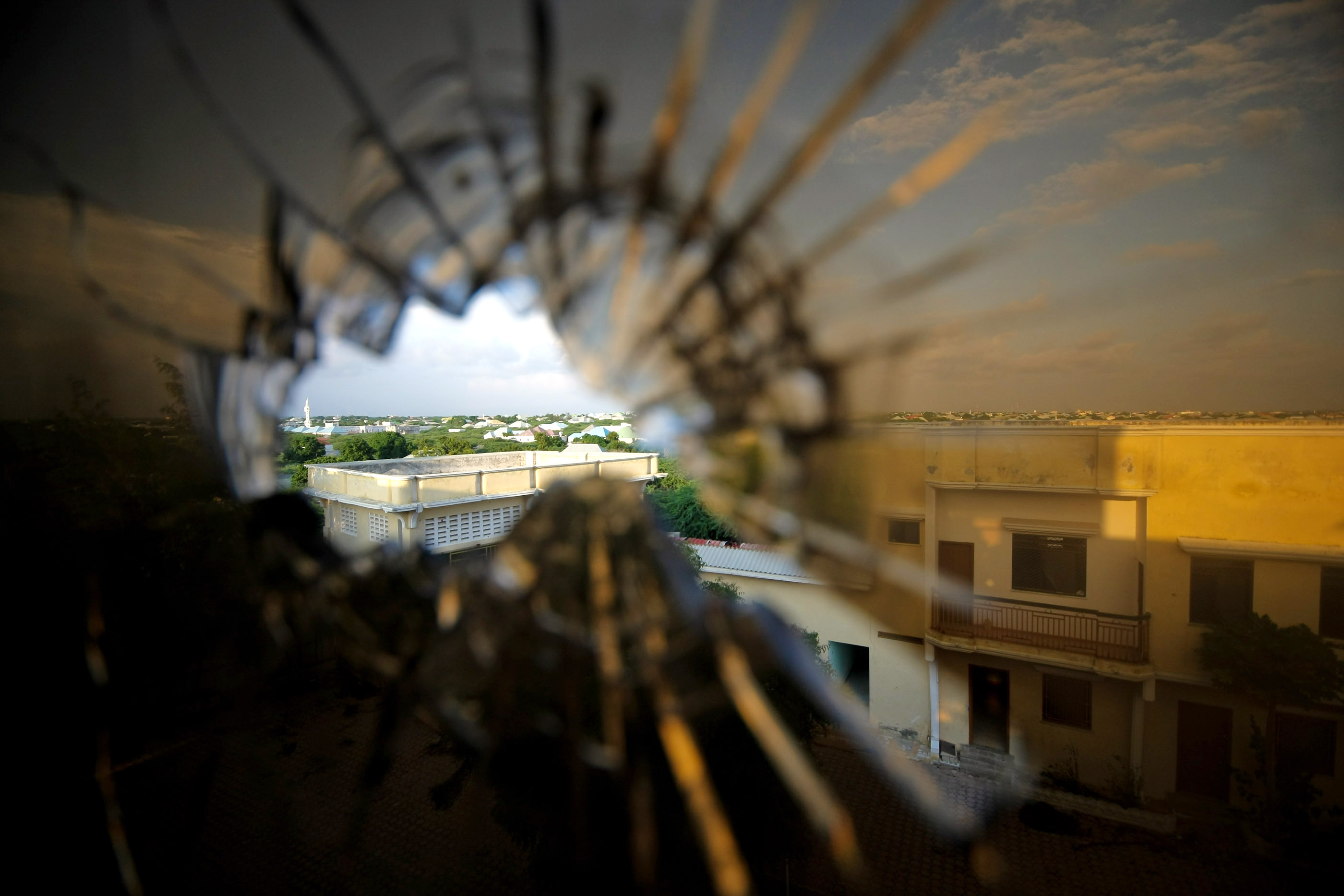Blick durch ein Ein­schuss­loch in einem Hotelfenster. Im Hintergrund ist der nörd­li­che Teil von Mo­ga­di­schu, der Hauptstadt von So­ma­lia,  zu sehen, wo Trup­pen der Afri­ka­ni­schen Uni­on ge­gen die Al-Shabab-Mi­liz ge­kämpft ha­ben.