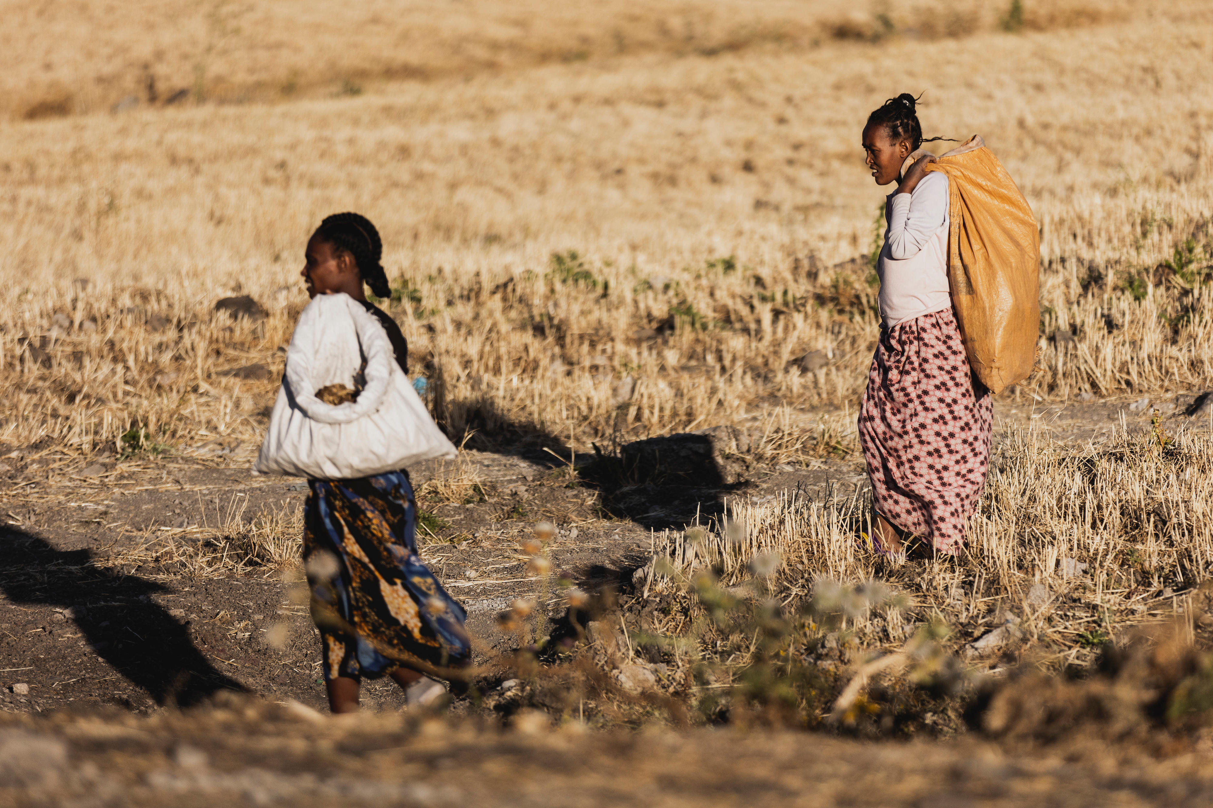 Zwei Frauen laufen über einen Acker in Addis Abeba, Äthiopien