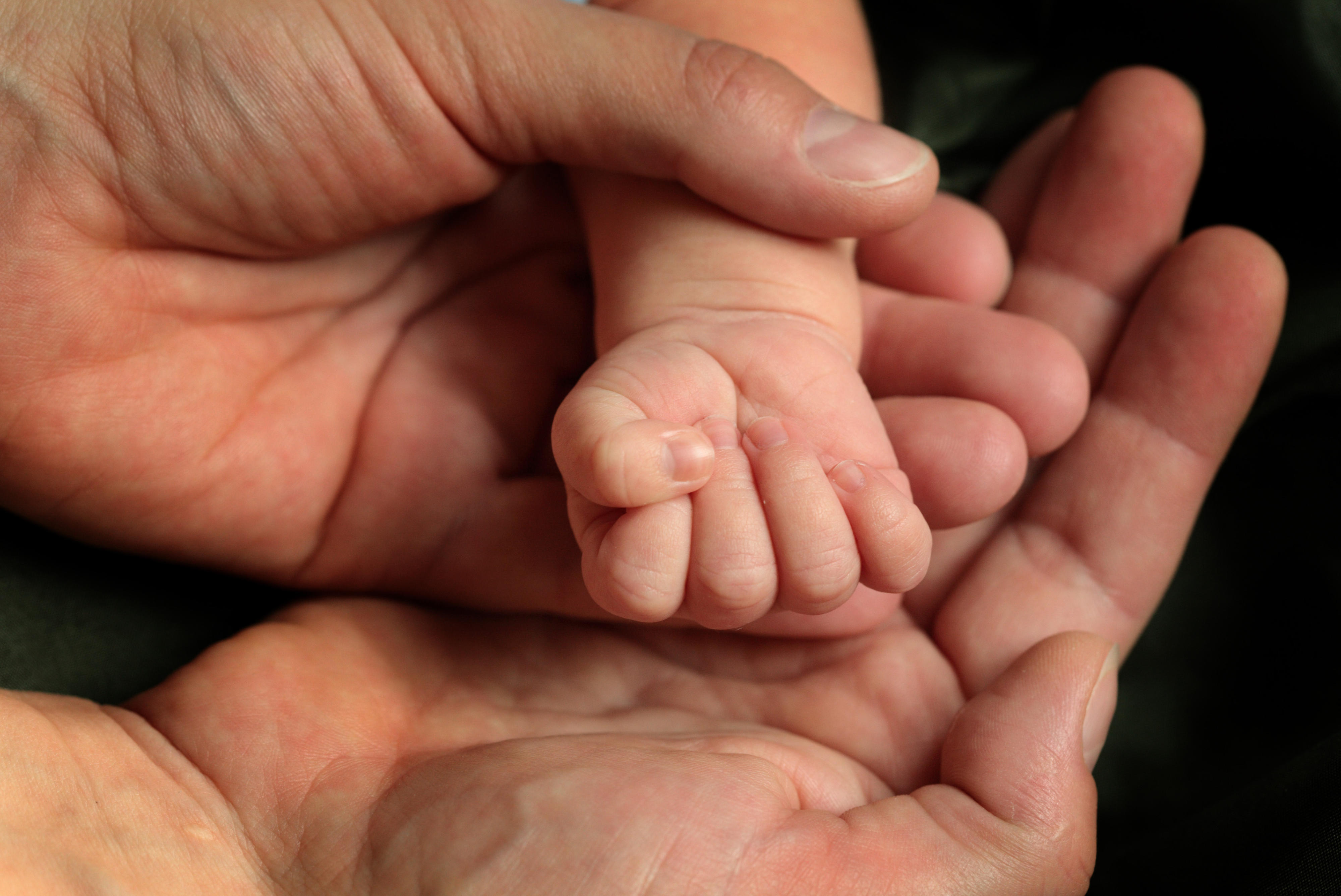 Erwachsenenhänge halten Babyhand (Symbolbild)