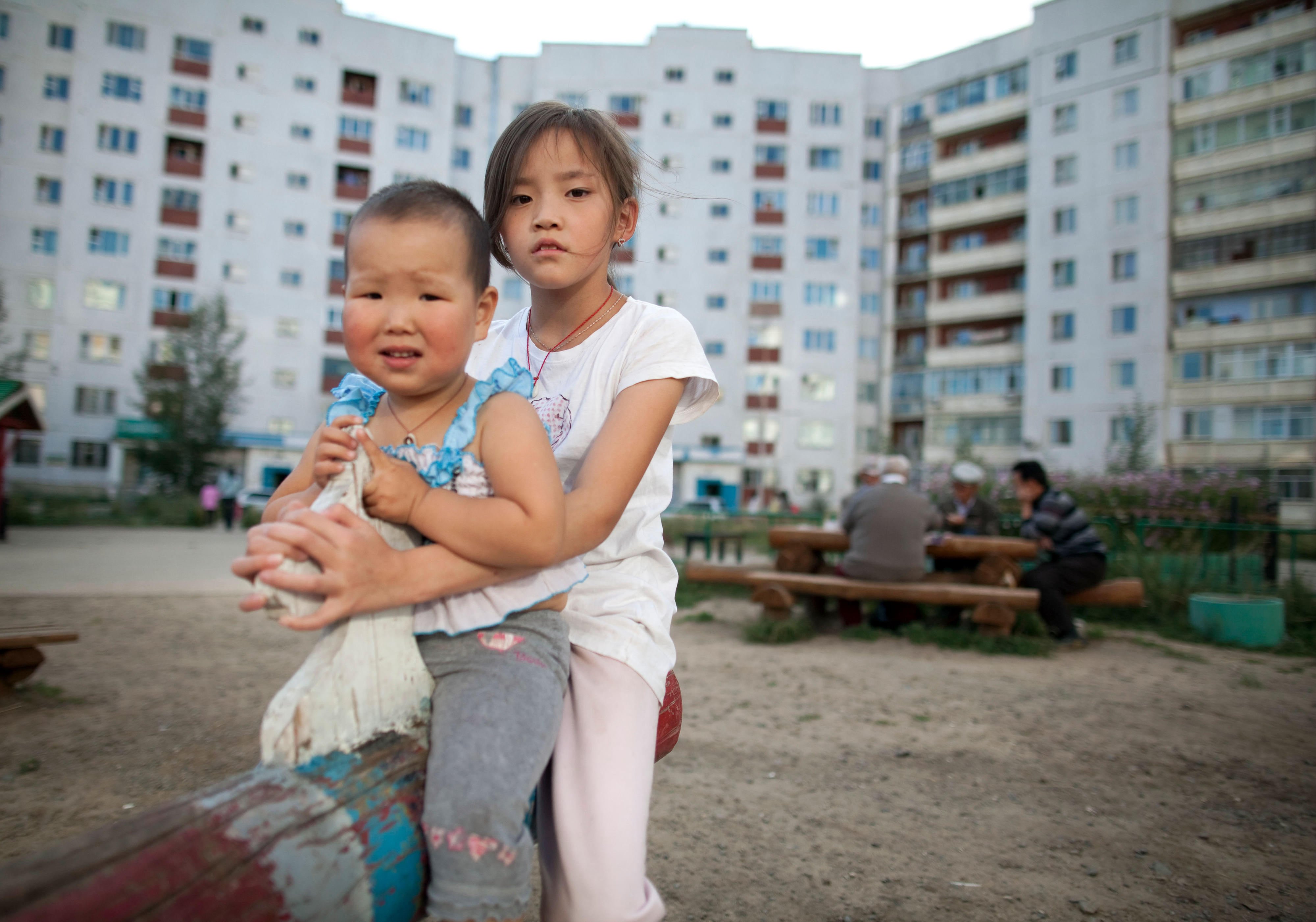 Kinder auf dem Spielplatz in einer Plattenbausiedlung in Ulan Bator, Mongolei 