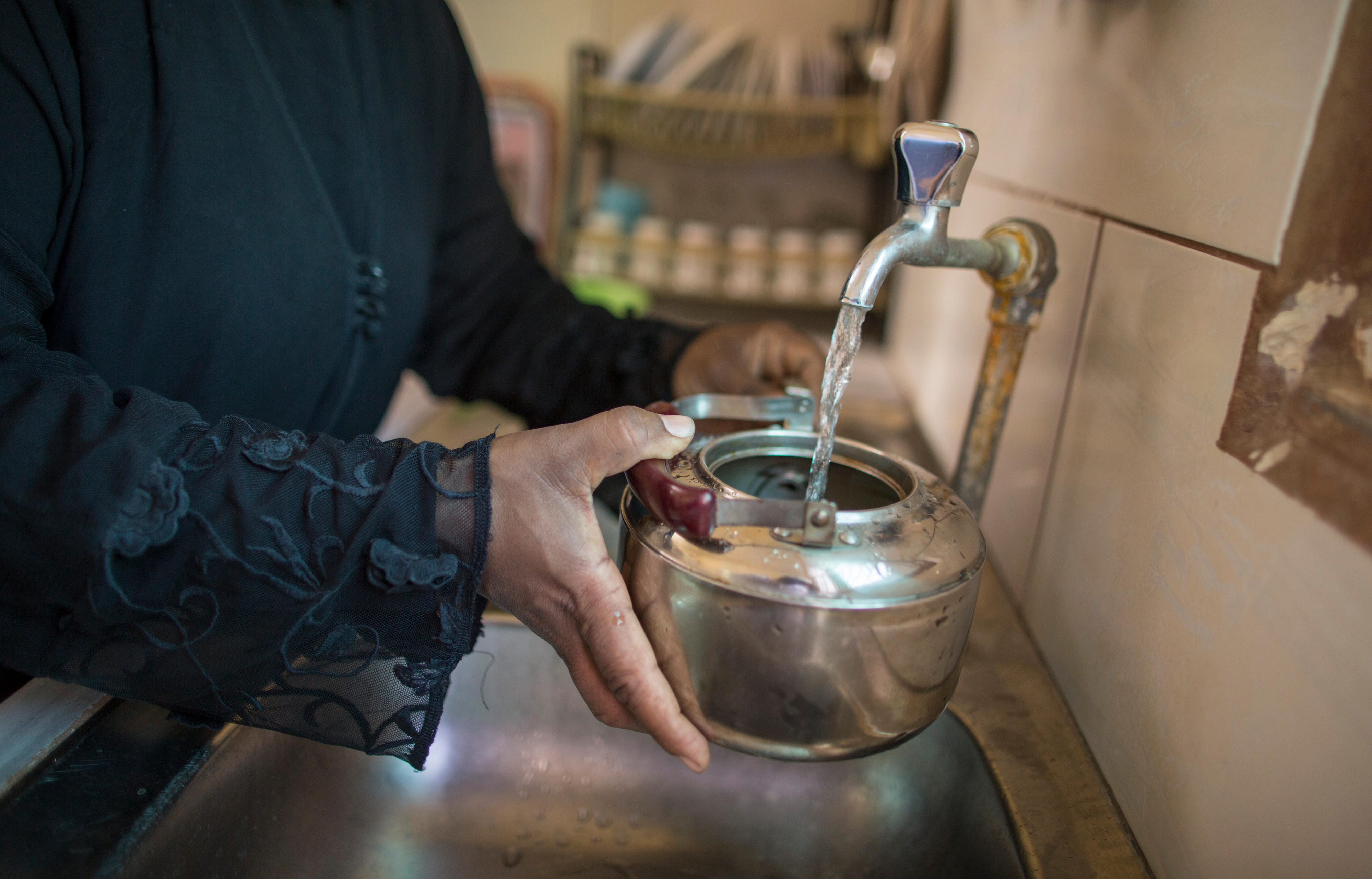 Eine Frau in Al Rawda/Kafrein (Jordanien) füllt frisches Wasser in eine Kanne.