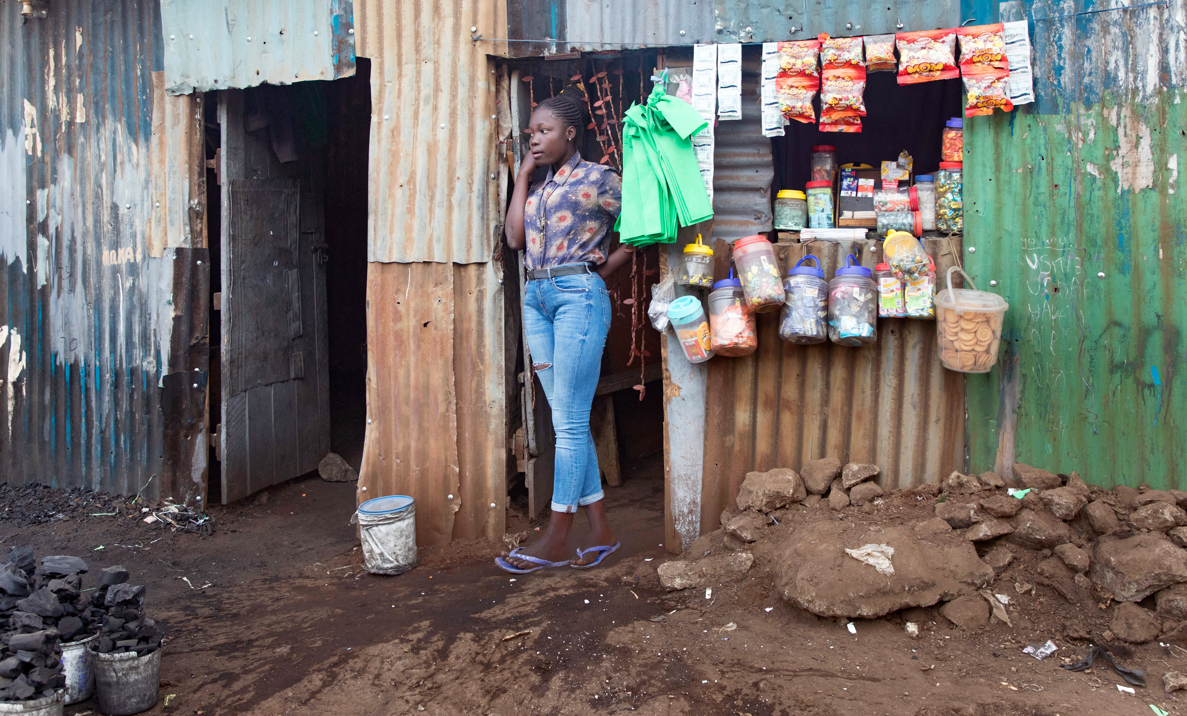 Junge Frau steht vor ihrem Laden in Kibera, einer informellen Siedlung in Nairobi, Kenia