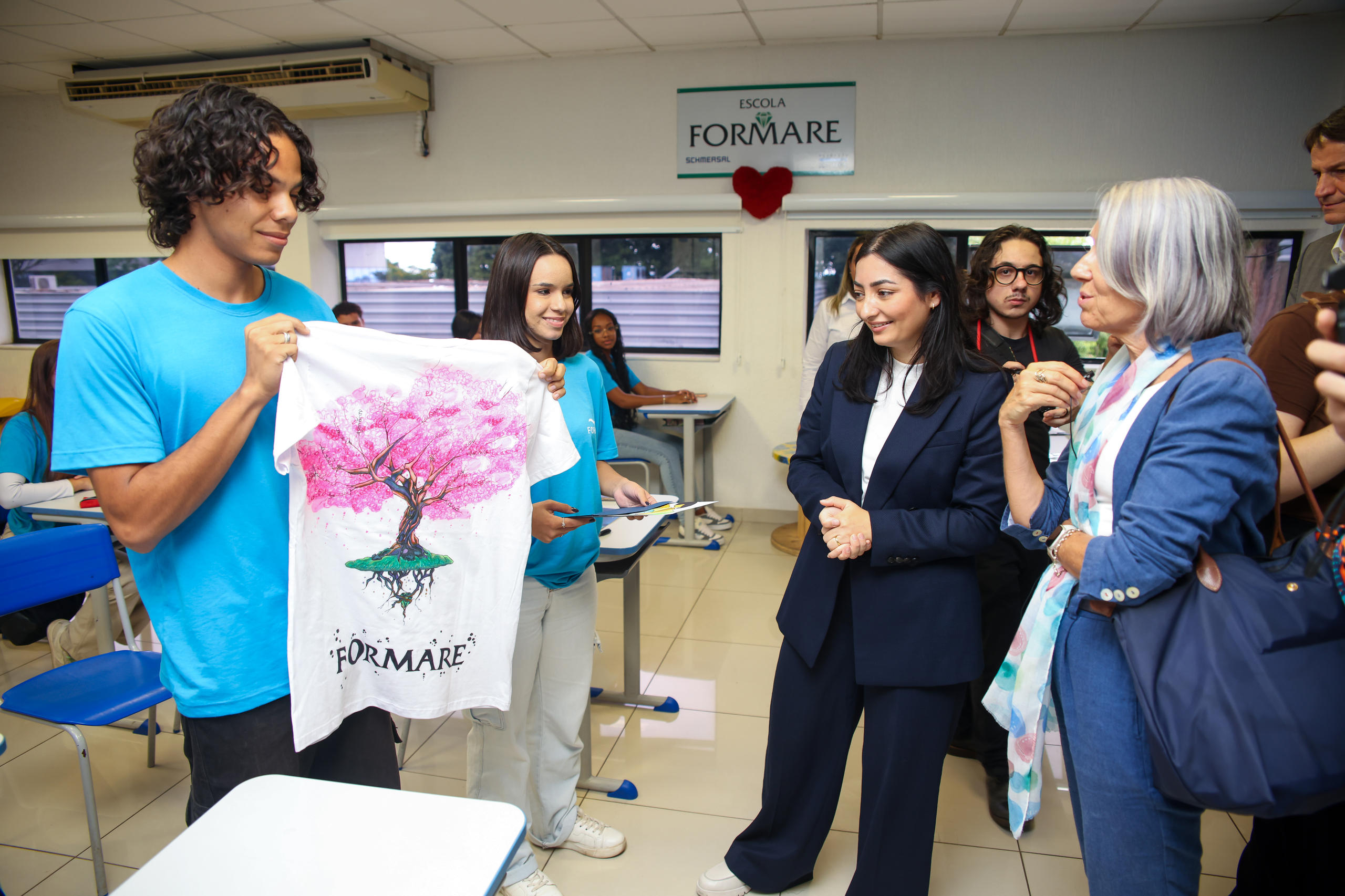 Foto von der Ministerin mit zwei Jugendlichen, die ein Tshirt hochhalten.