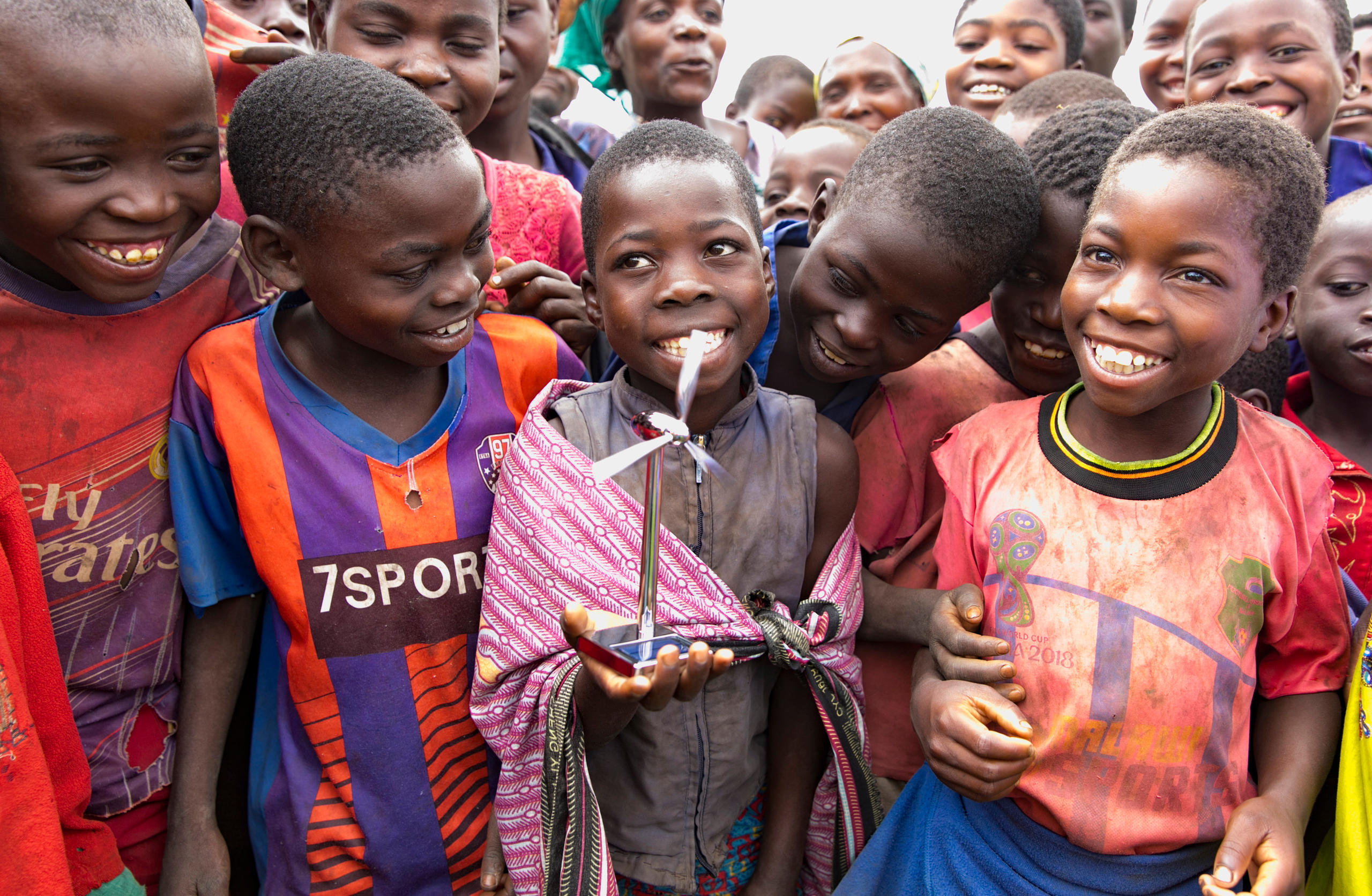 Kinder in einem Dorf in Malawi halten ein Spielzeugwindrad in der Hand
