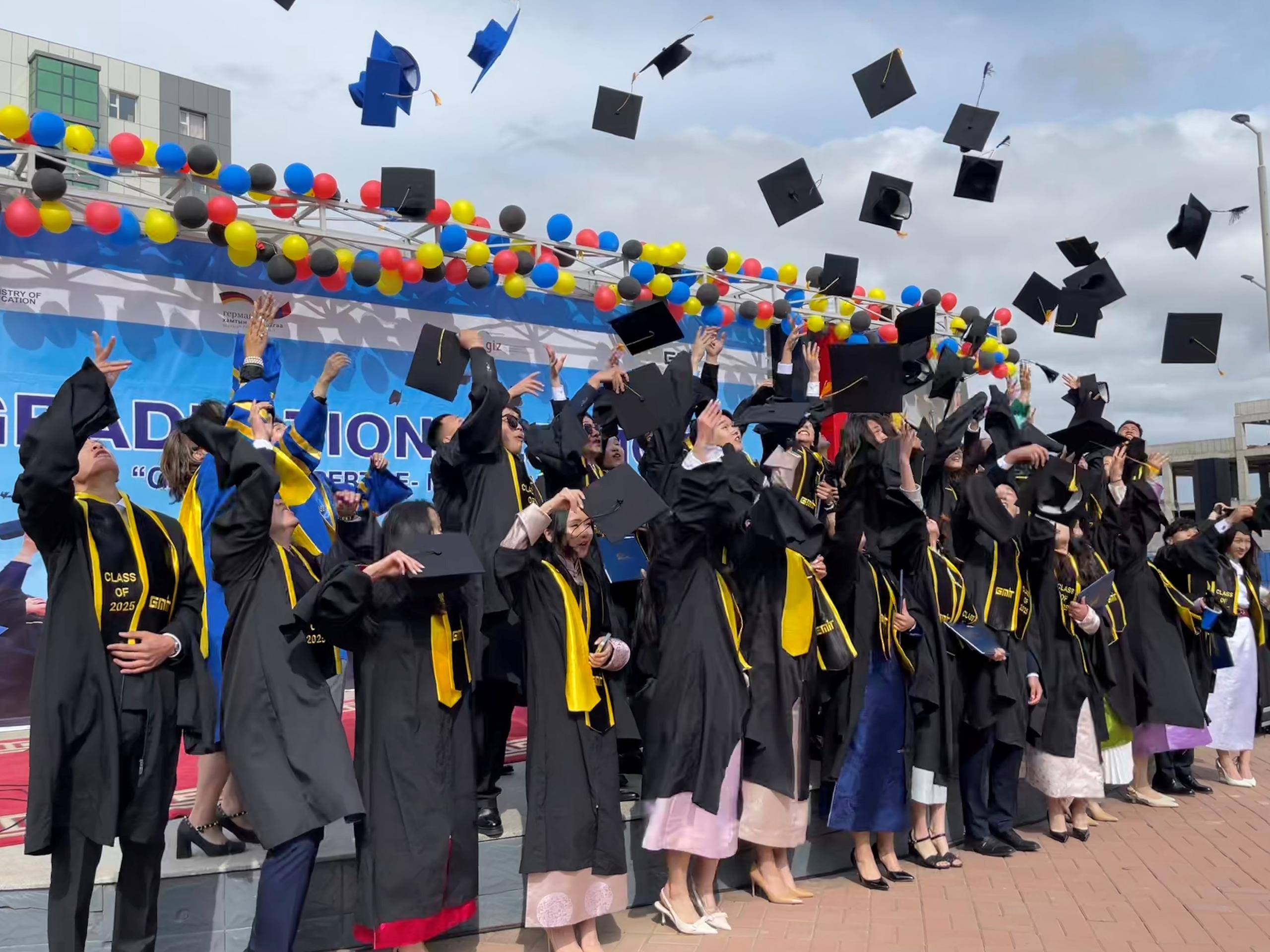 Foto von Absolventen einer Hochschule, die ihre Hüte in die Luft schmeißen.