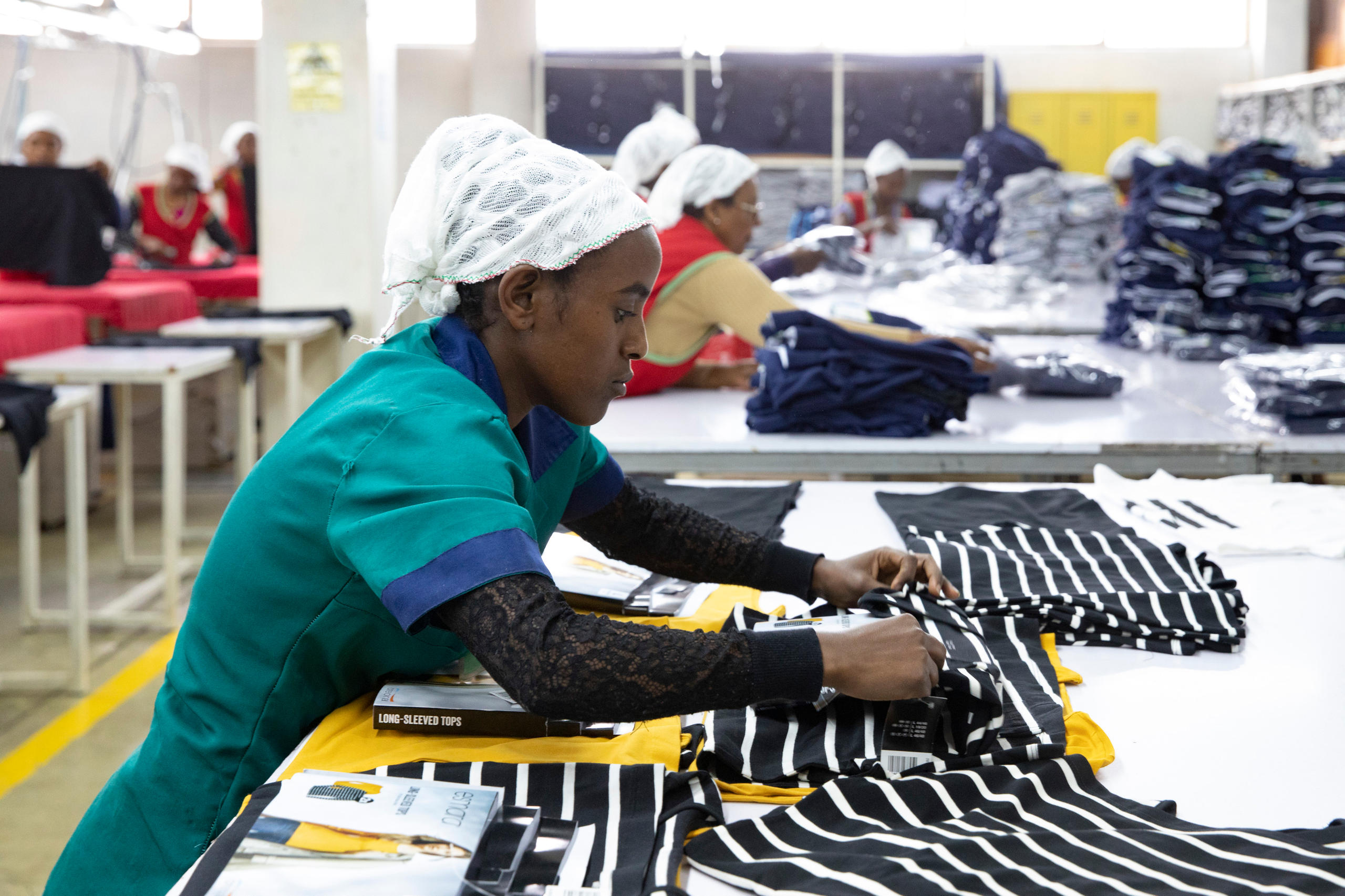 Foto von einer Frau, die T-Shirts näht.