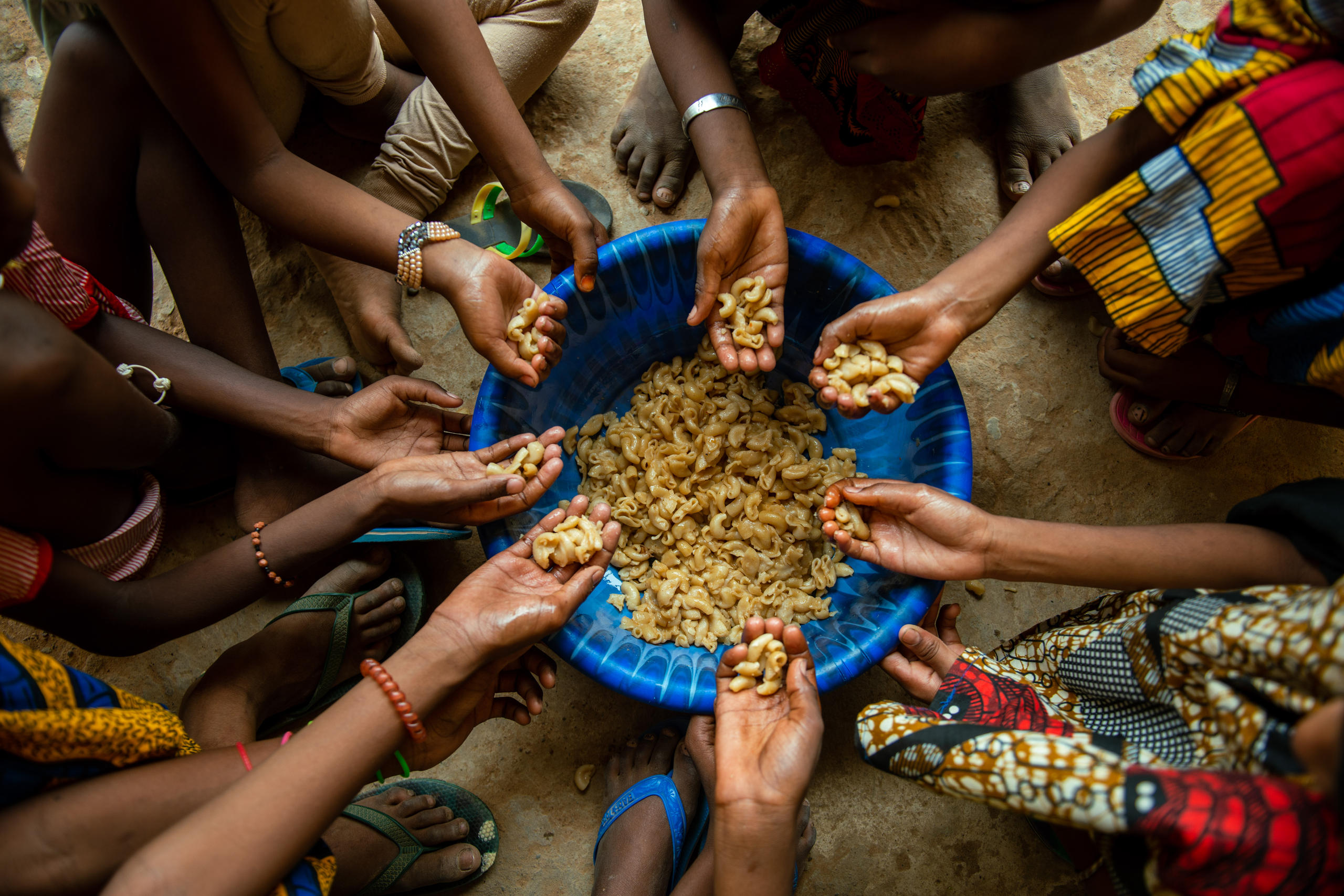 Foto von Händen, die Nudeln aus einer Schüssel nehmen.