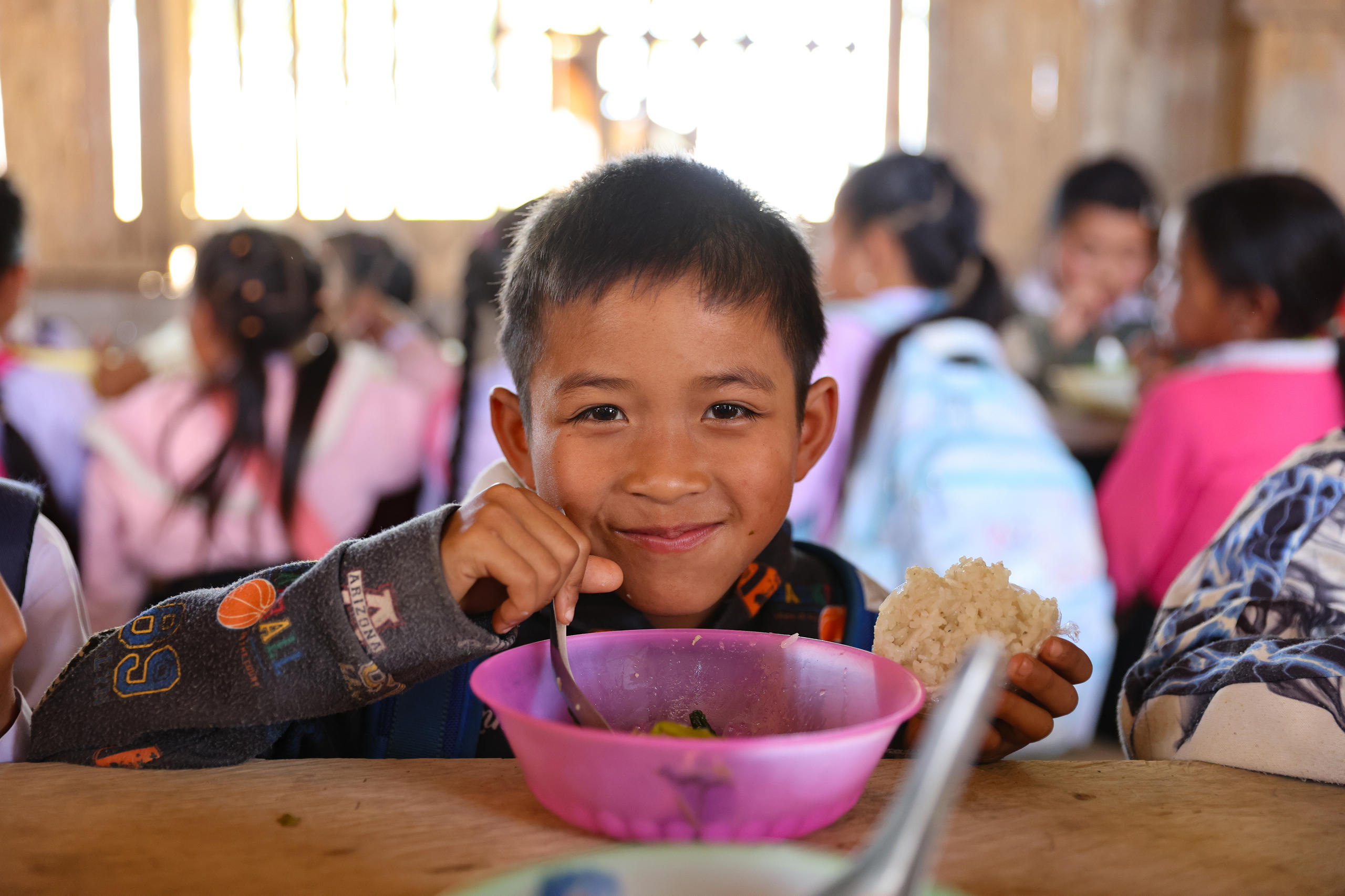 Foto von einem Jungen, der aus einer pinken Schüssel isst.