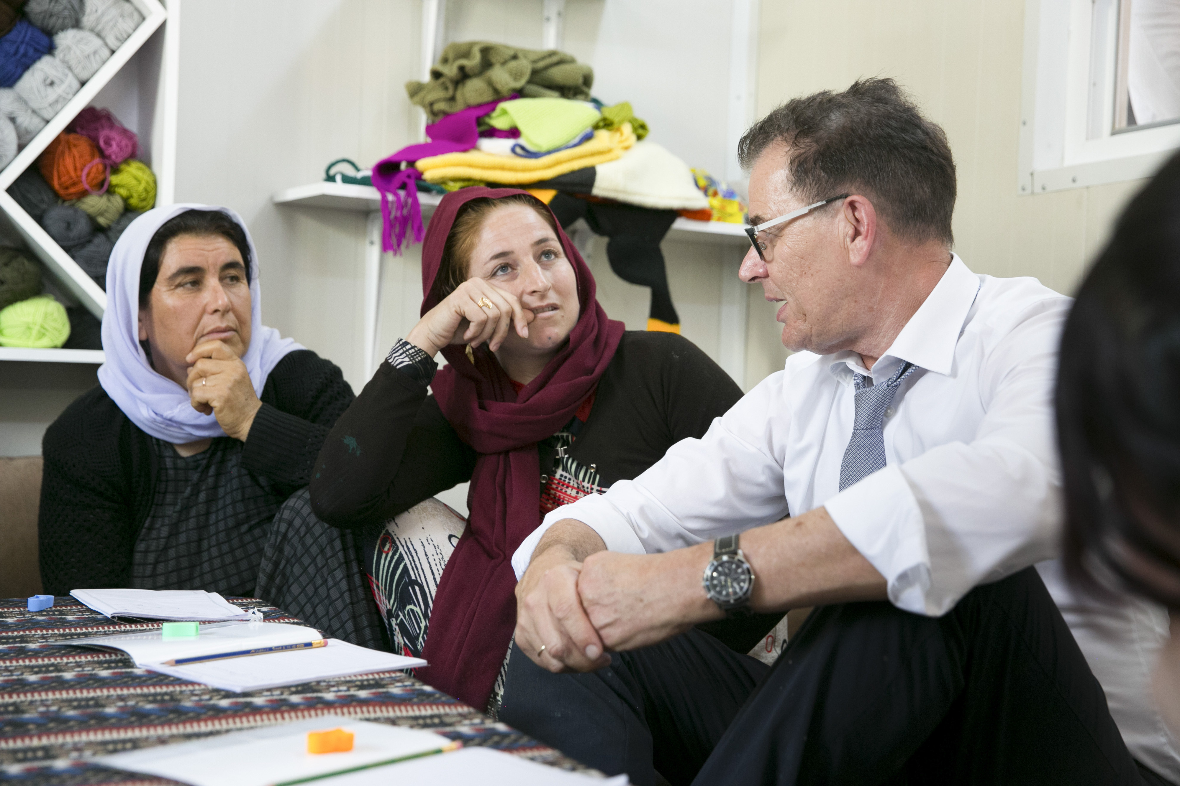 Bundesentwicklungsminister Gerd Müller unterhält sich in einem Flüchtlingscamp im Irak mit jesidischen und muslimischen Frauen, die an einem Alphabetisierungsprogramm teilnehmen. 