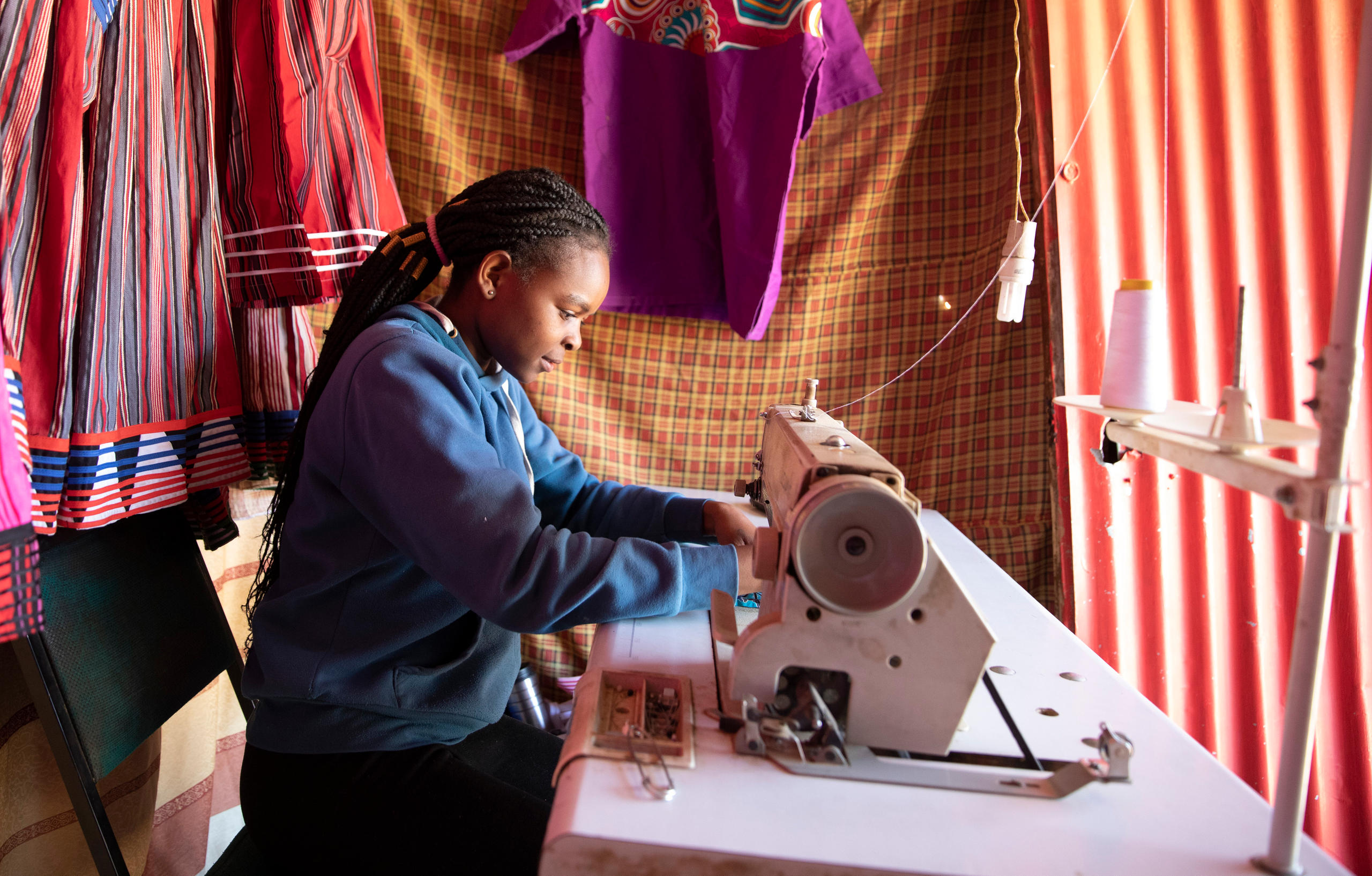 Maedchen an einer Naehmaschine in einer Schneiderei in der informellen Siedlung Katutura in Windhoek