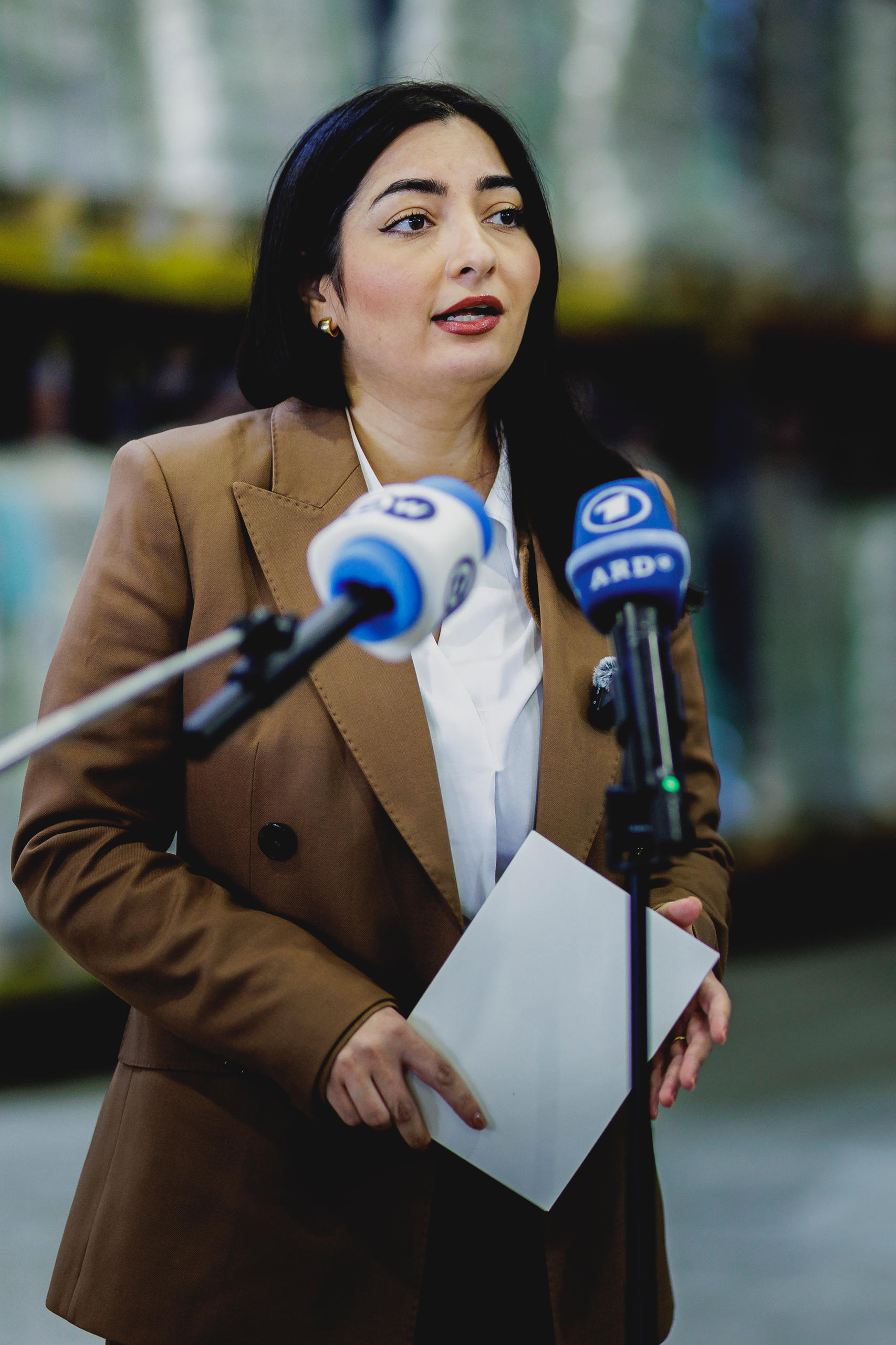 Ministerin Alabali Radovan in braunem Jackett vor Pressemikrofonen