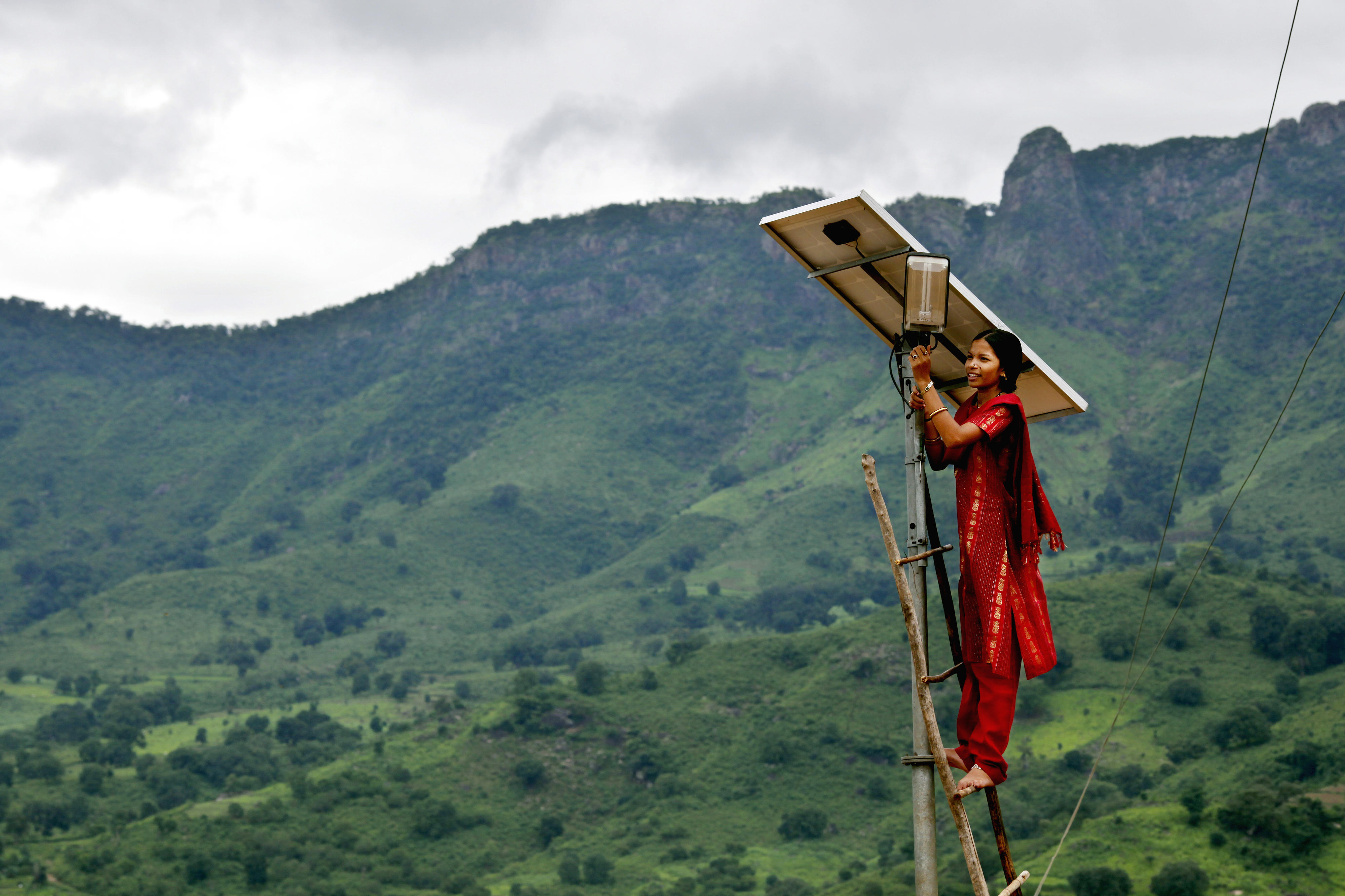 Eine Solaringenieurin überprüft eine solarbetriebene Straßenlaterne in Indien.