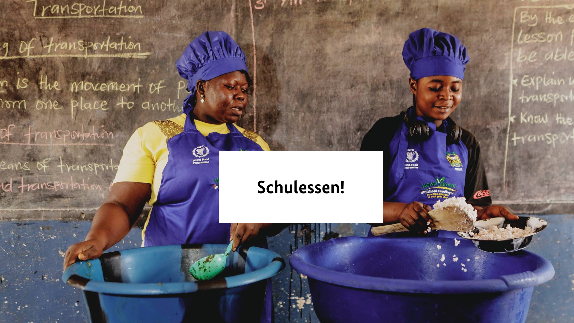 Zwei Frauen mit blauen Hauben schöpfen Teller Essen auf einen Teller in der Mitte des Bildes steht "Schulessen!".