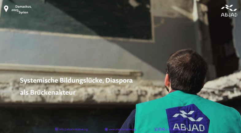 Person mit grünem ABJAD-Westen blickt auf eine beschädigte Wand in Damaskus.