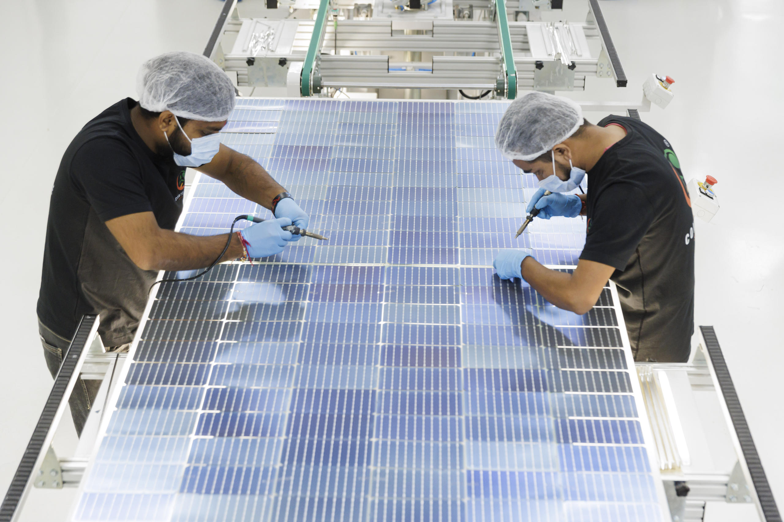 Zwei Männer arbeiten mit elektrischen Geräten an einem Solarpanel.
