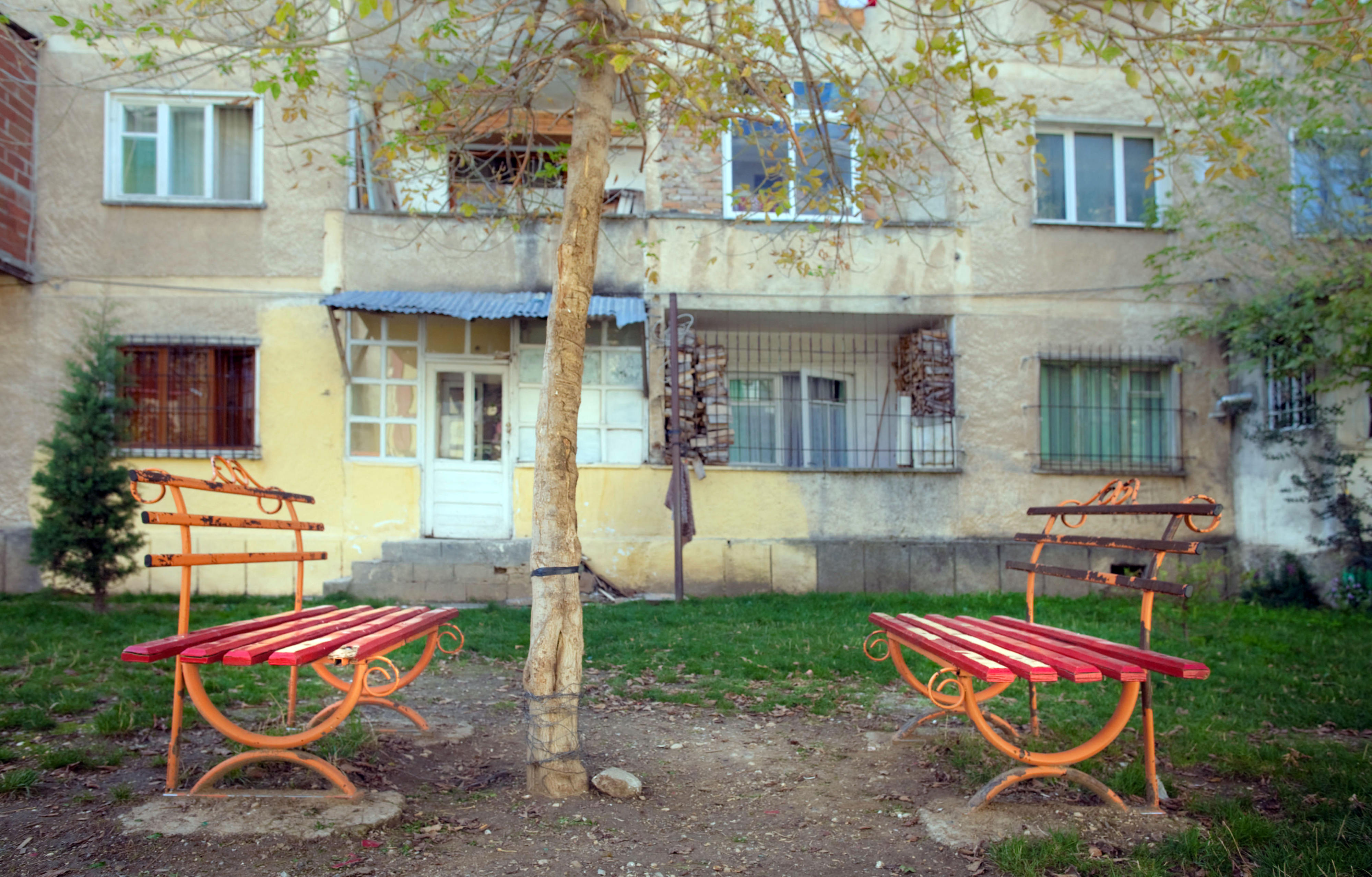 Zwei alte rote Sitzbänke im Garten eines Wohnhauses in Pogradec, Albanien