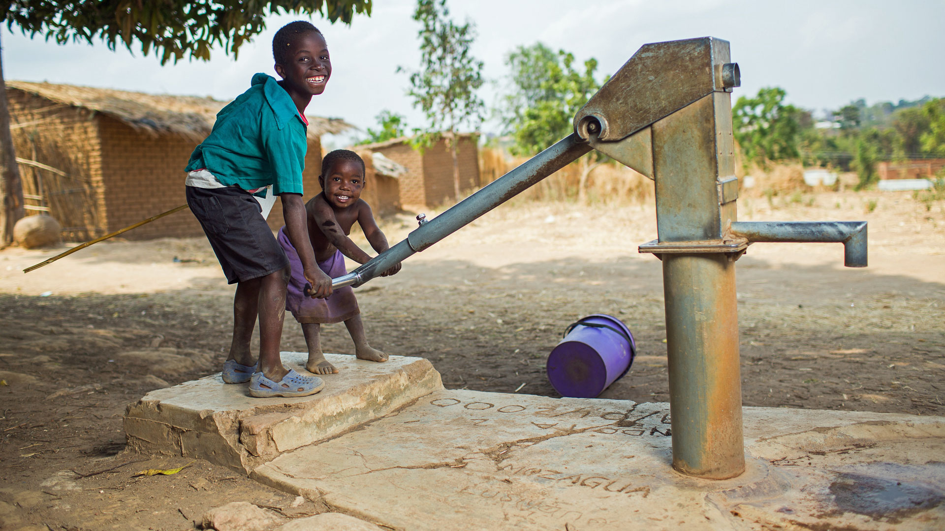 In einem Dorf nahe Bilira (Malawi) spielen zwei Kinder mit der Wasserpumpe eines Brunnens.