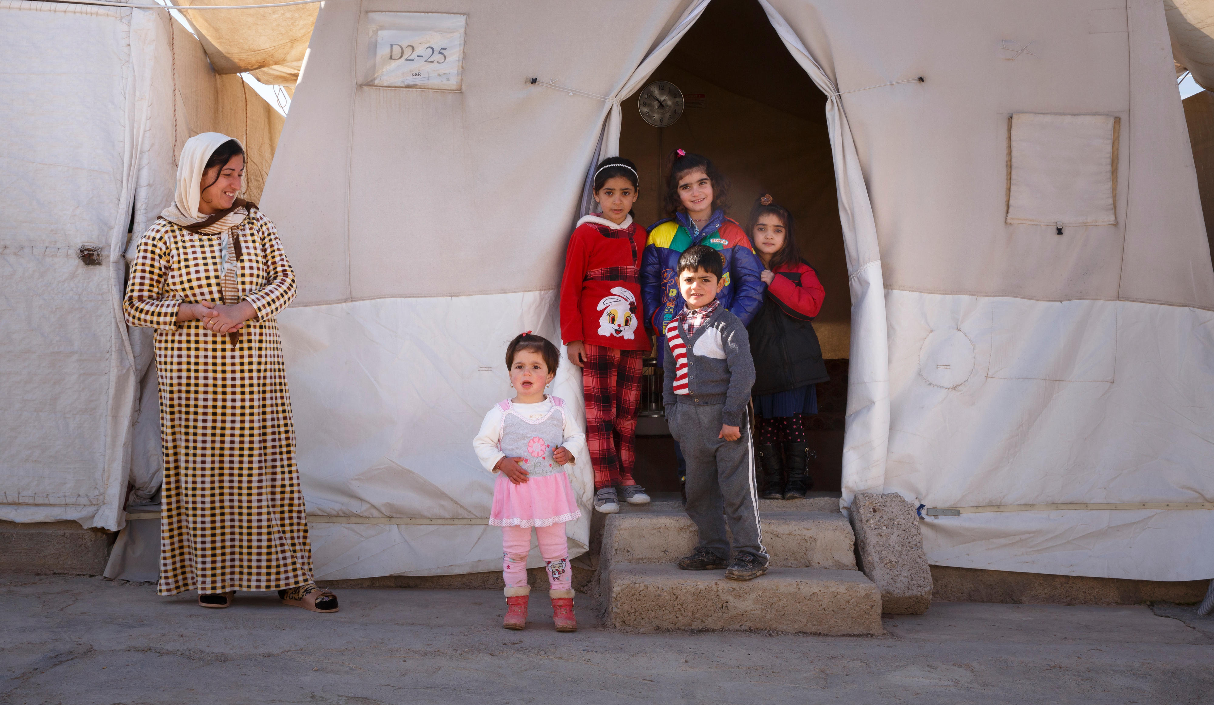 Ei­ne Frau mit ih­rer Fa­mi­lie im Flücht­lings­camp Shariya, ein Camp für je­si­di­sche Bin­nen­flücht­lin­ge in Do­huk, Nord­irak