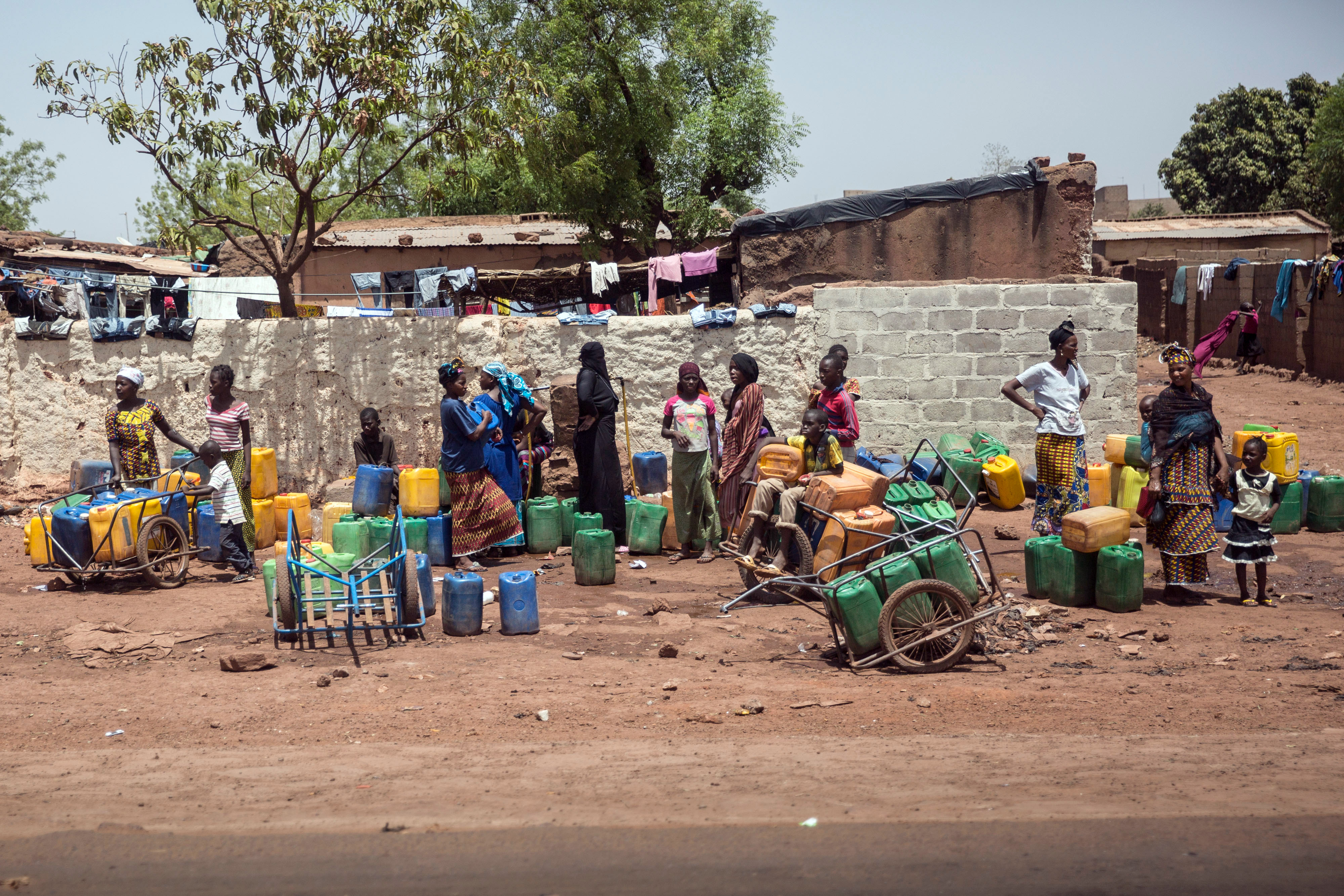 Frauen stehen mit Wasserkanistern an einer Straße in Bamako.