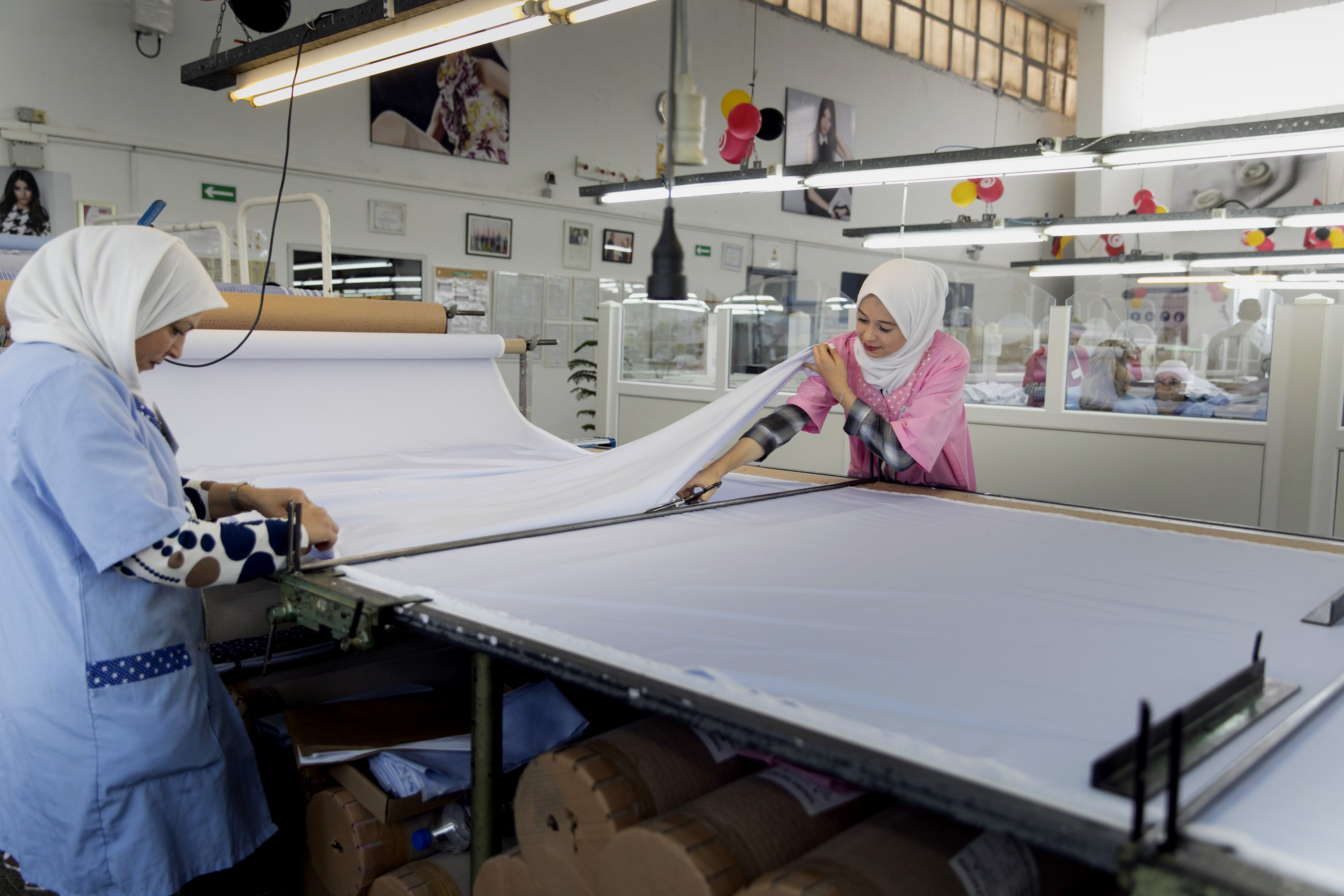 Two women cut a cotton fabric in a textile factory in Bizerte.