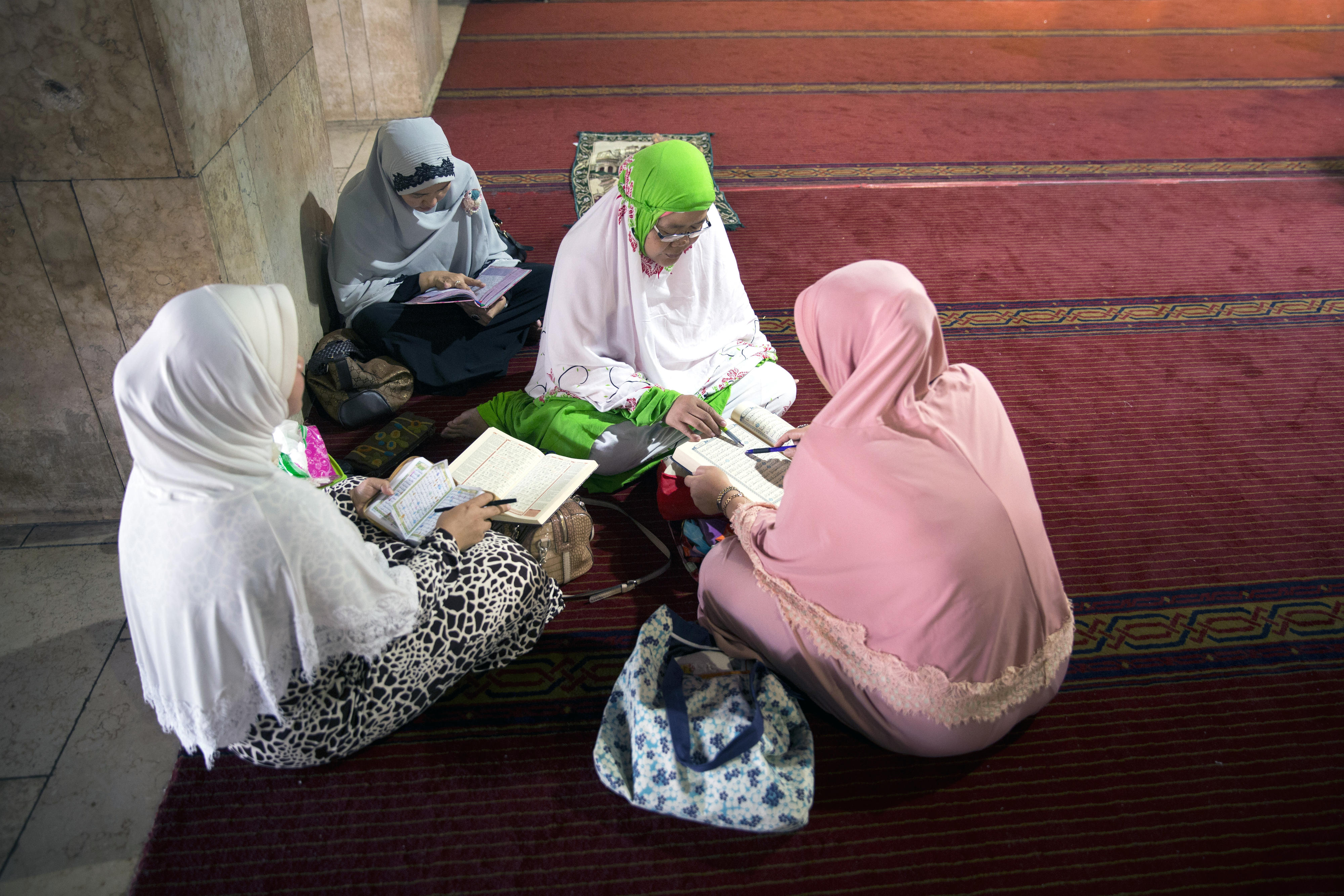 Women reading and interpreting the Koran in the Istiqlal Mosque in Jakarta, Indonesia