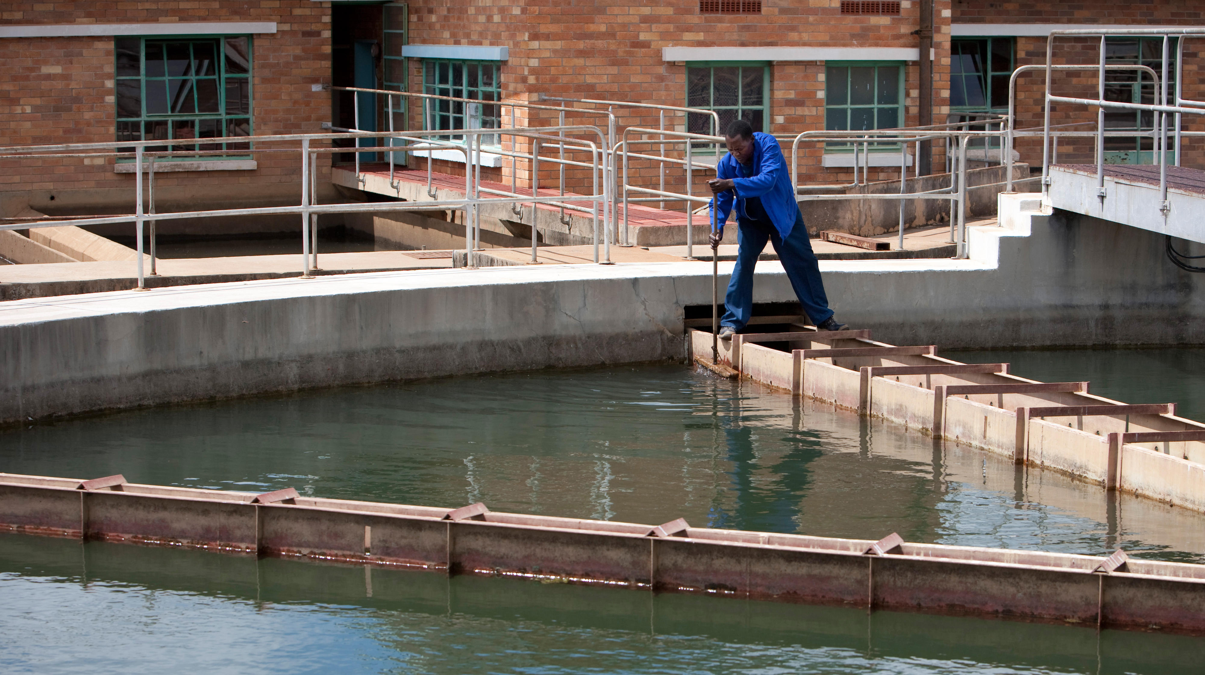 Mitarbeiter bei der Reinigung eines Filterbeckens eines Wasserwerkes in Livingstone, Sambia