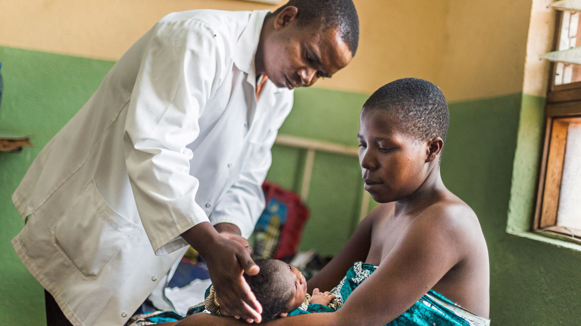 A mother has her child examined by a doctor