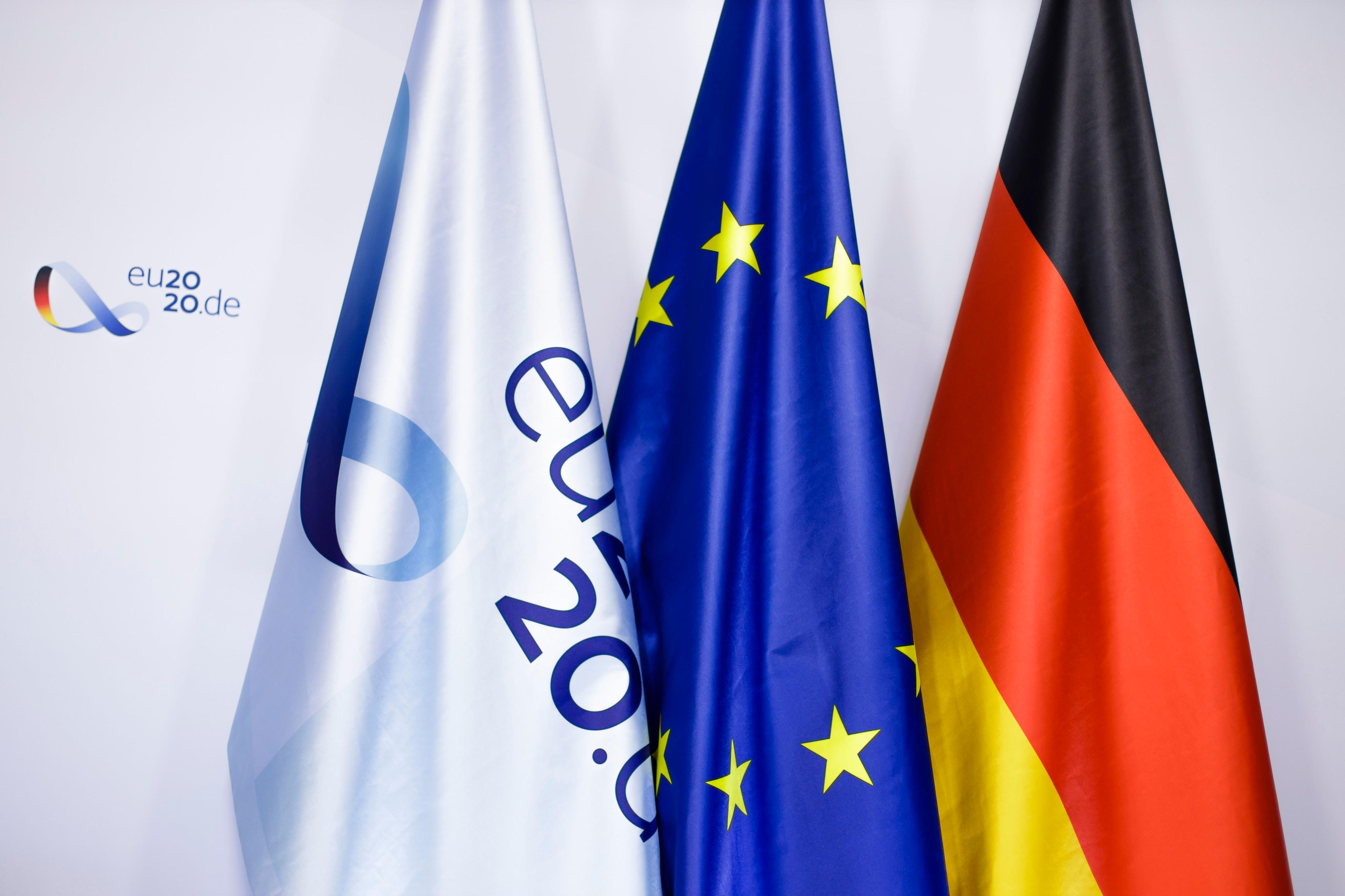 Flag­ge mit dem Lo­go der deut­schen EU-Rats­prä­si­dent­schaft 2020, Eu­ro­pa-Flag­ge und Deutsch­land-Flag­ge