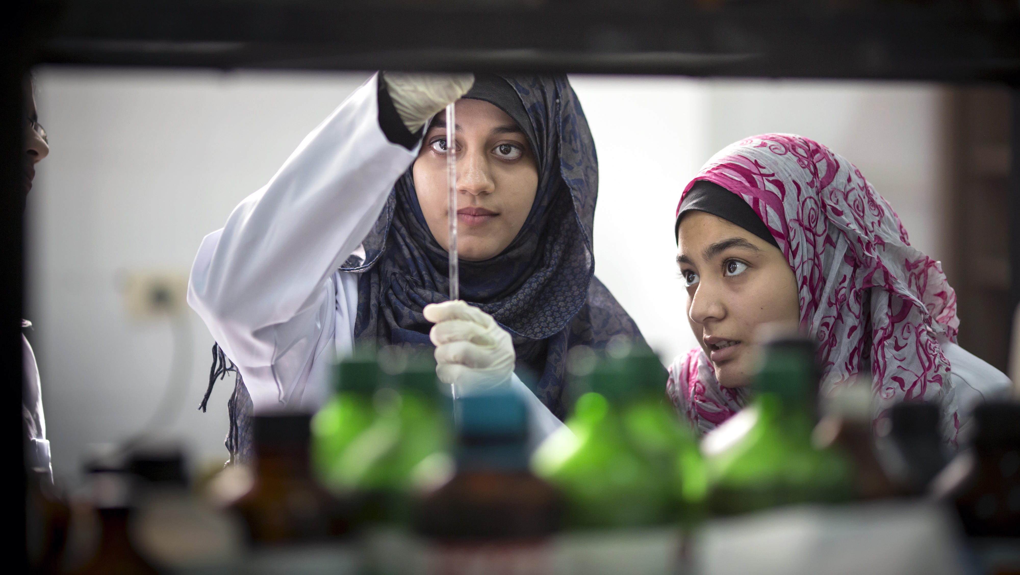Pharmakologiestudentinnen in einem Labor an der Al-Azhar Universität in Gaza-Stadt. Eine der Frauen hält eine Pipette in Augenhöhe und schaut gemeinsam mit der anderen Studentin auf die Skala der Pipette.