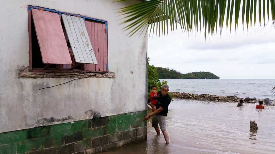 Ein Mann zeigt an seinem Haus auf St. Lucia, wie hoch die letzte Überschwemmung war.