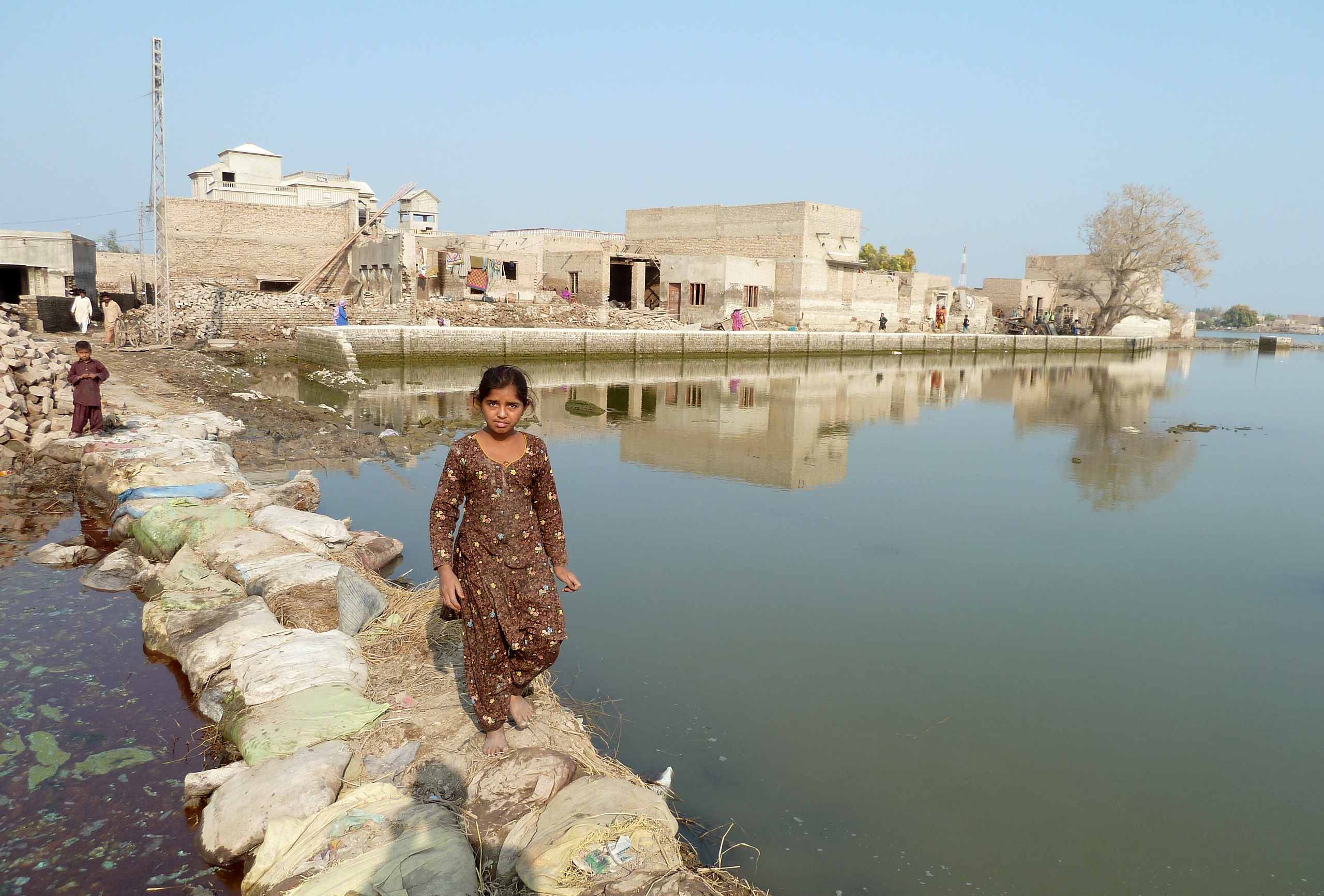 Ein junges Mädchen steht auf einer Behelfsbrücke aus Sandsäcken, nach einer Überflutung in der Provinz Sindh in Pakistan.