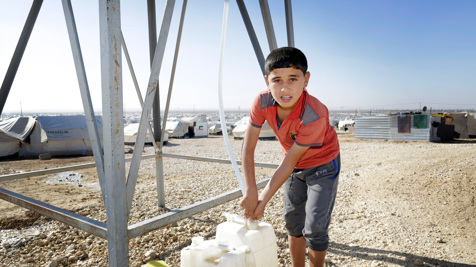 Ein Junge zapft im jordanischen Flüchtlingslager Zaatari Wasser aus einem Tank.